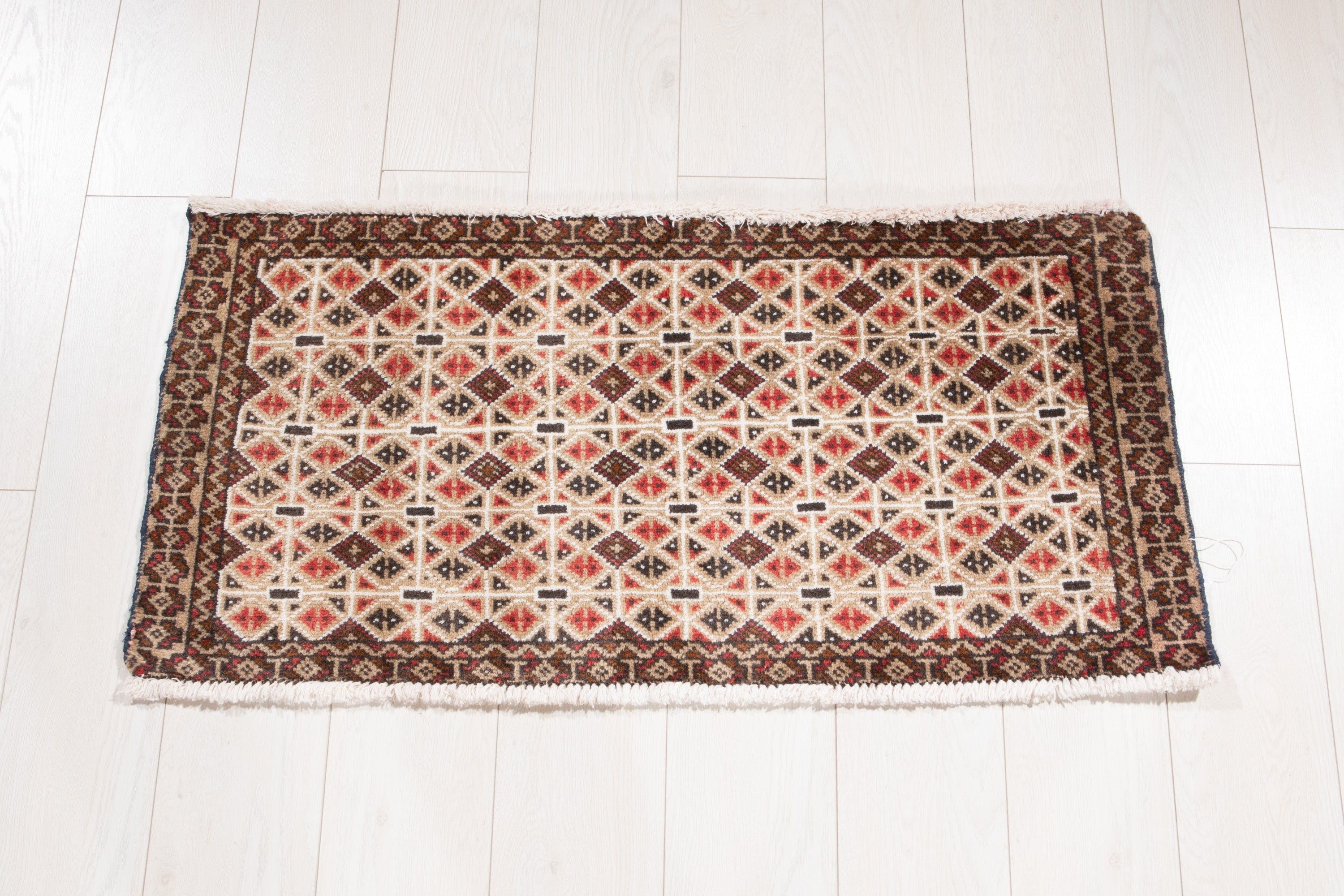 Full view of the small beige and brown Persian rug with an all-over geometric diamond pattern.
