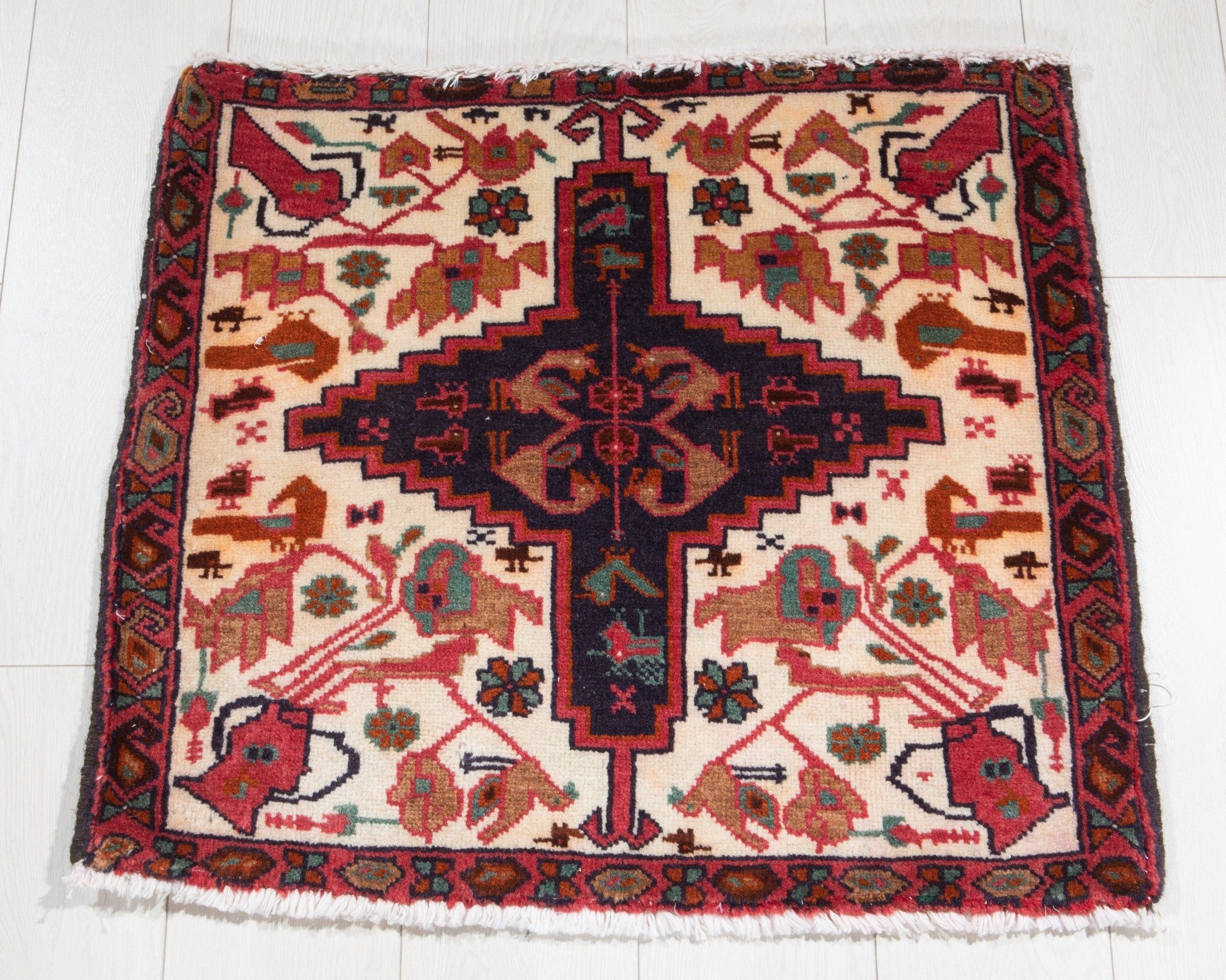 Full view of the beige Heriz Persian rug with a navy diamond medallion and bird motifs.