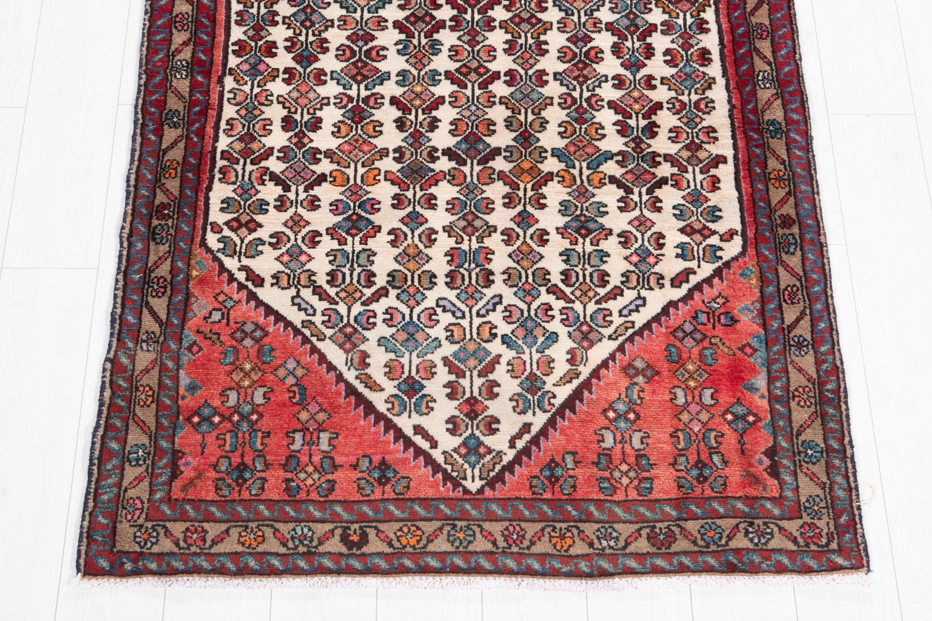 Close-up of coral medallion end on beige Hamadan Persian runner, multi-band border detail