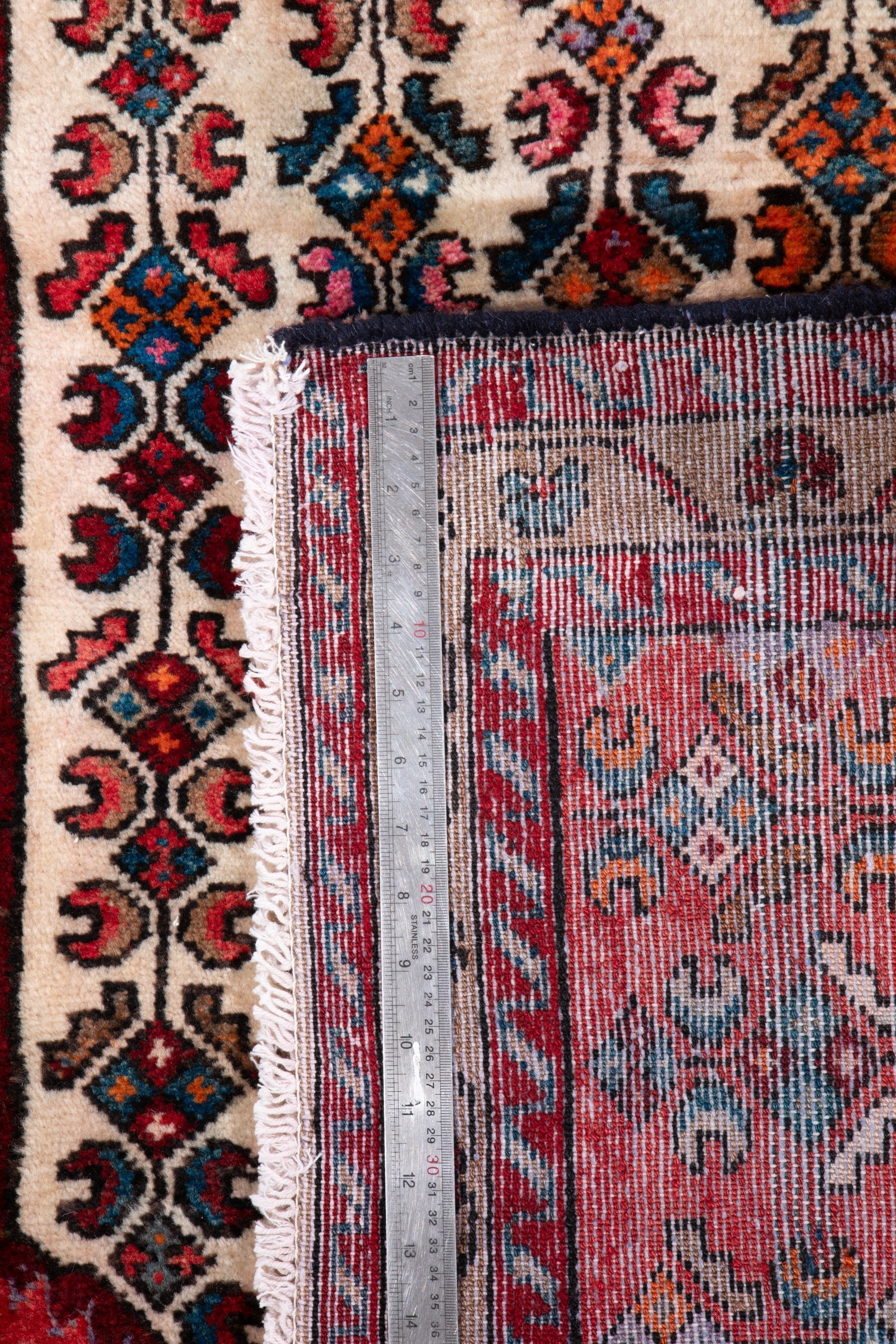 Back of Hamadan Persian runner rug with ruler measuring knot density and pile structure