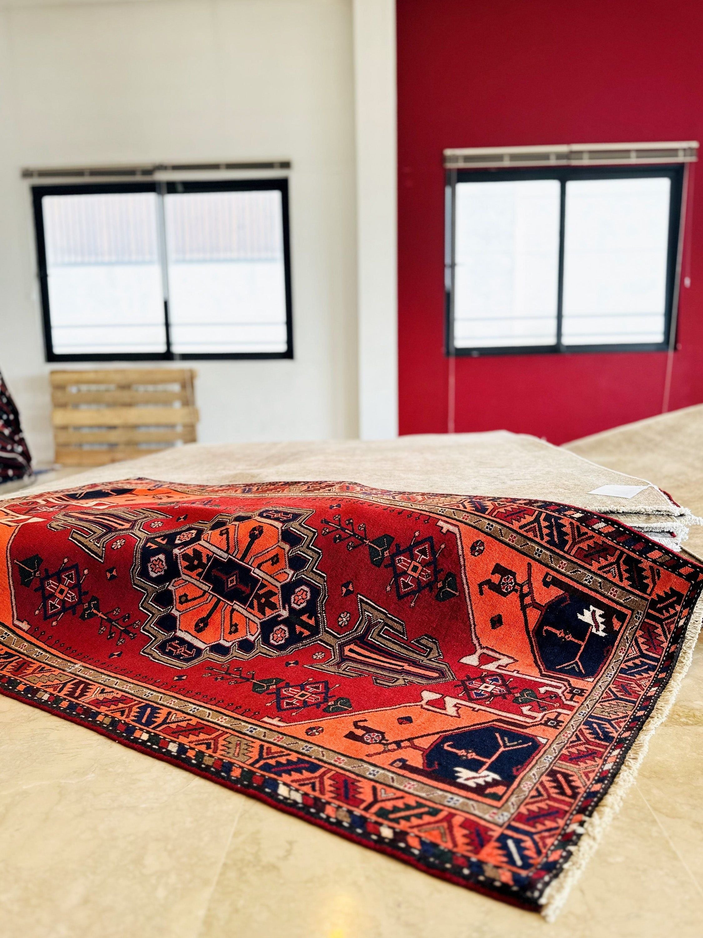 Rug partly unrolled in a warehouse, showing the geometric medallion pattern up close.