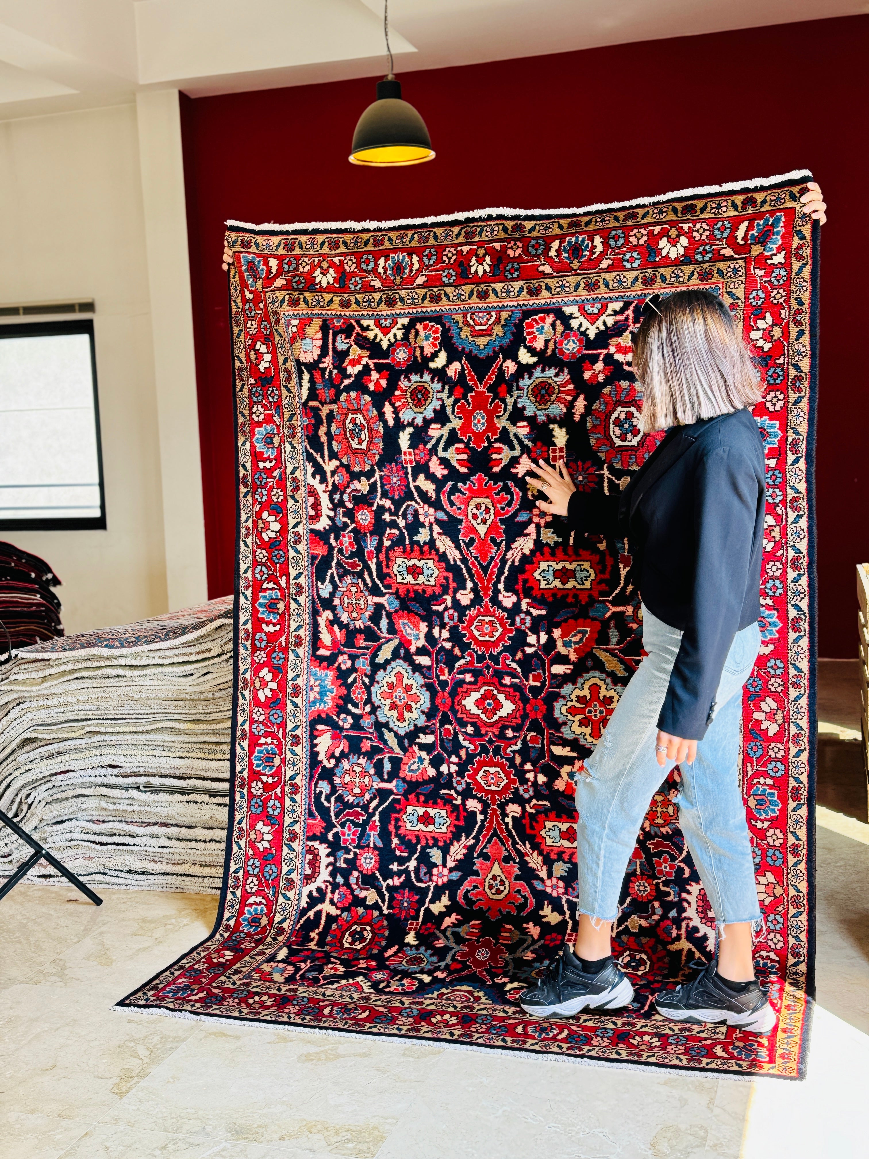 Woman holding Hand-Knotted Vintage Wool Area Rug – 8' 2" x 5' 4" showcasing its size and detailed craftsmanship in a home setting.