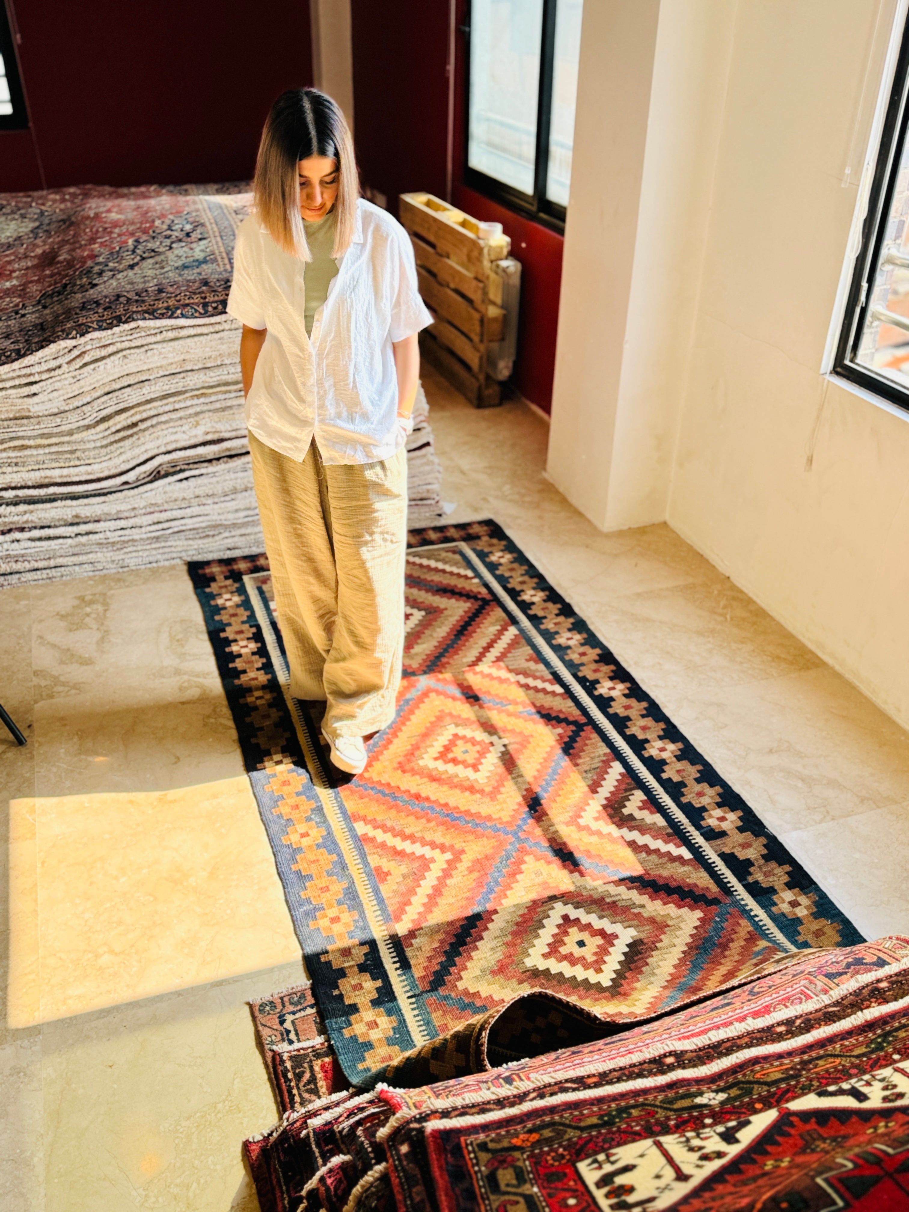 Lifestyle shot of a woman walking on the kilim rug in a sunlit room.