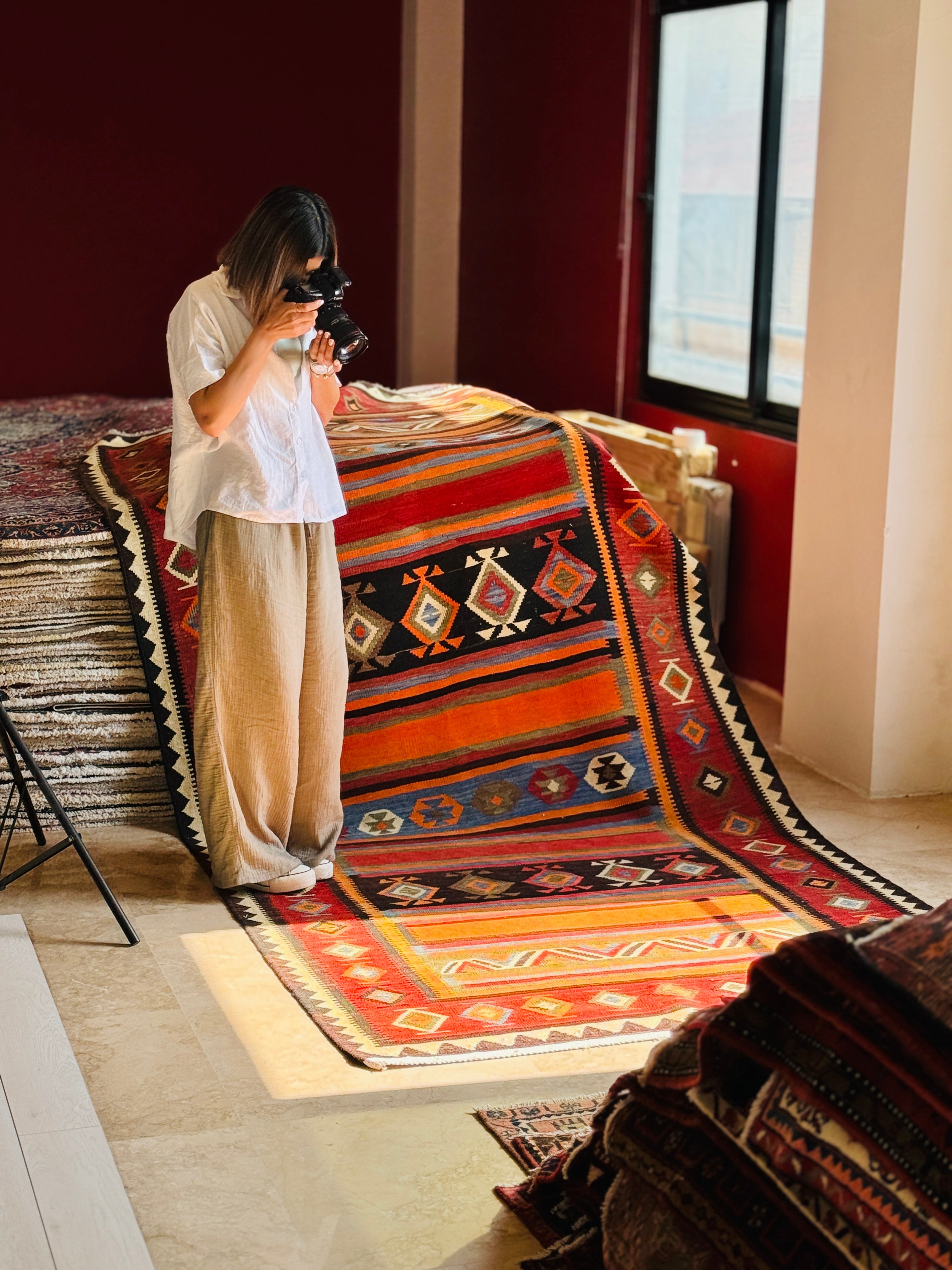 Showroom shot of the vintage kilim rug hanging vertically as it is photographed.