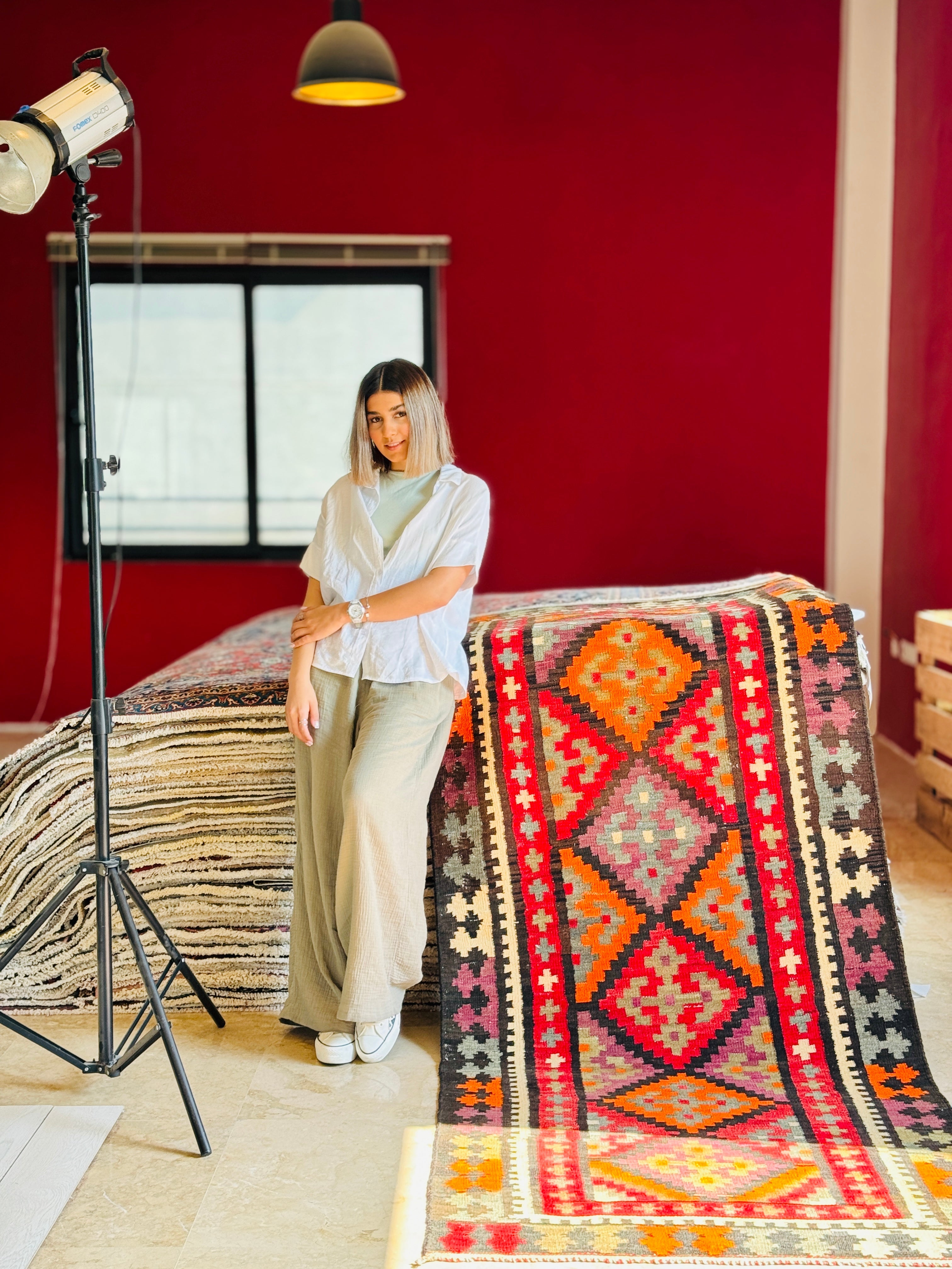 Studio photo shoot of the orange kilim runner hanging beside a woman posing.