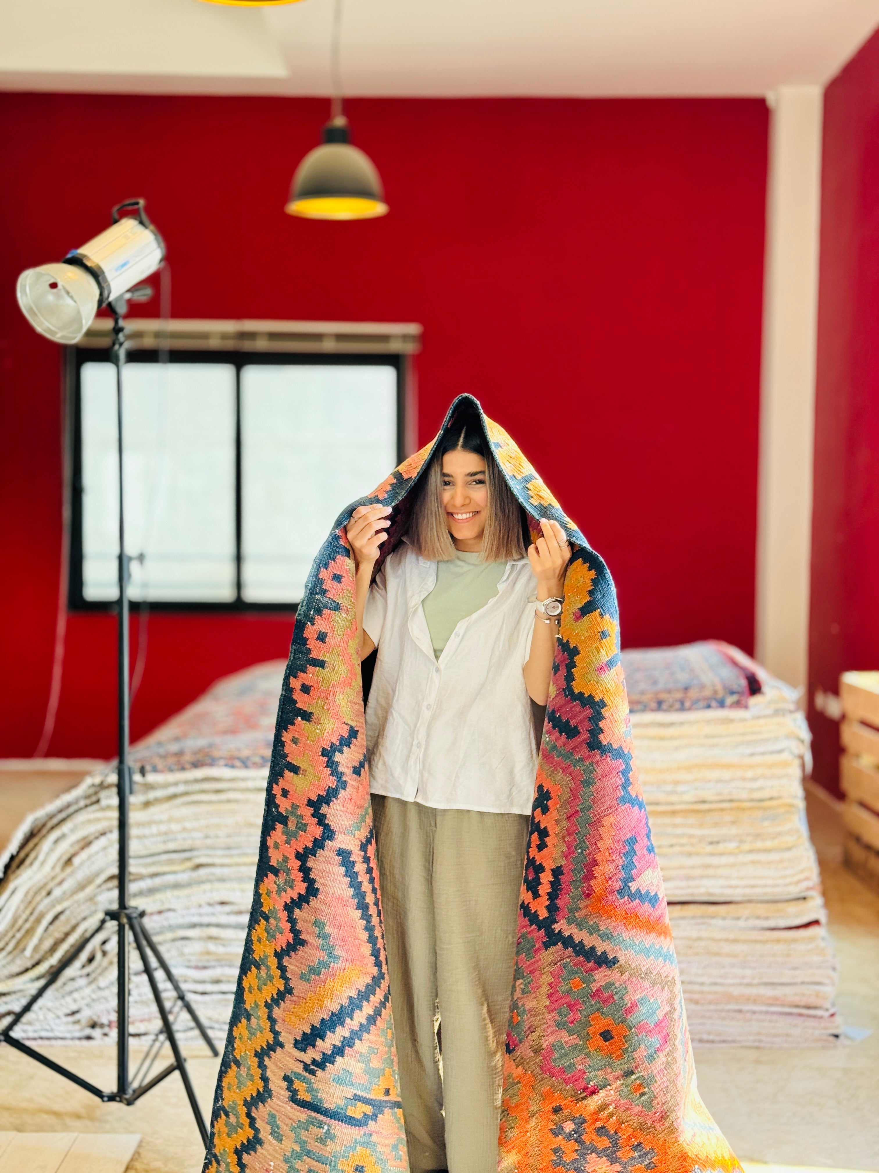 Studio photo shoot of a woman playfully draping the runner rug over her head.