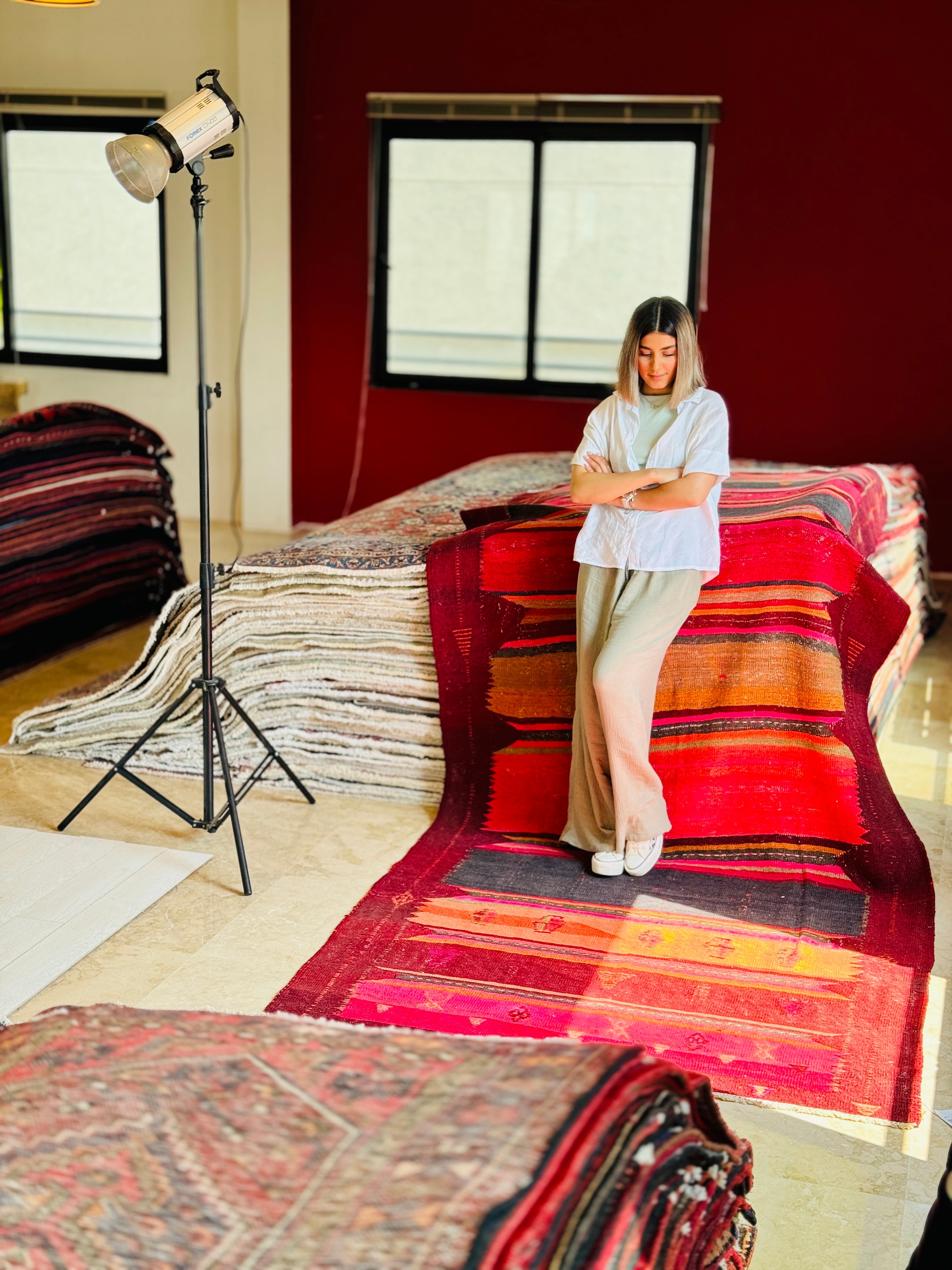Studio photo shoot of the striped kilim rug with a woman standing on it.