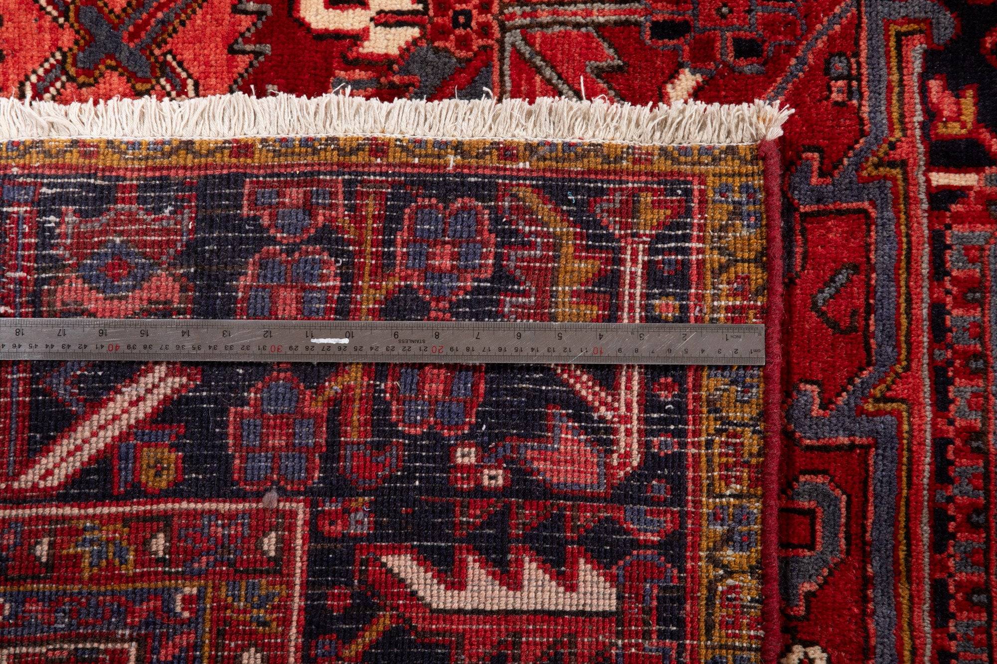 Measuring tape across the rug's end, showing the fringe and detailed border pattern.