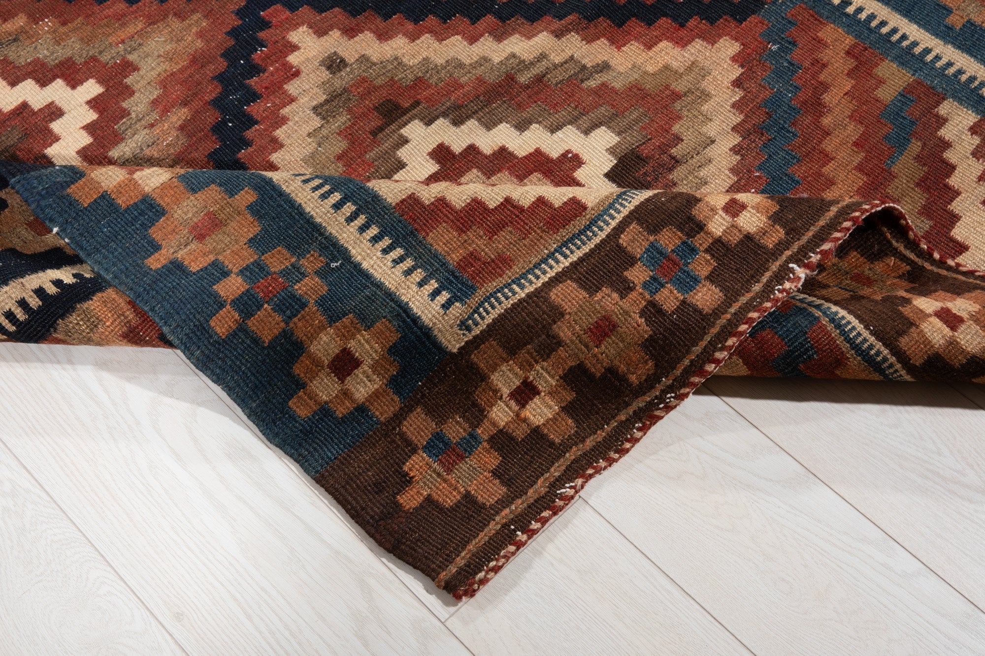 Corner of the kilim folded back, showing the flatweave back and finished edge stitching.
