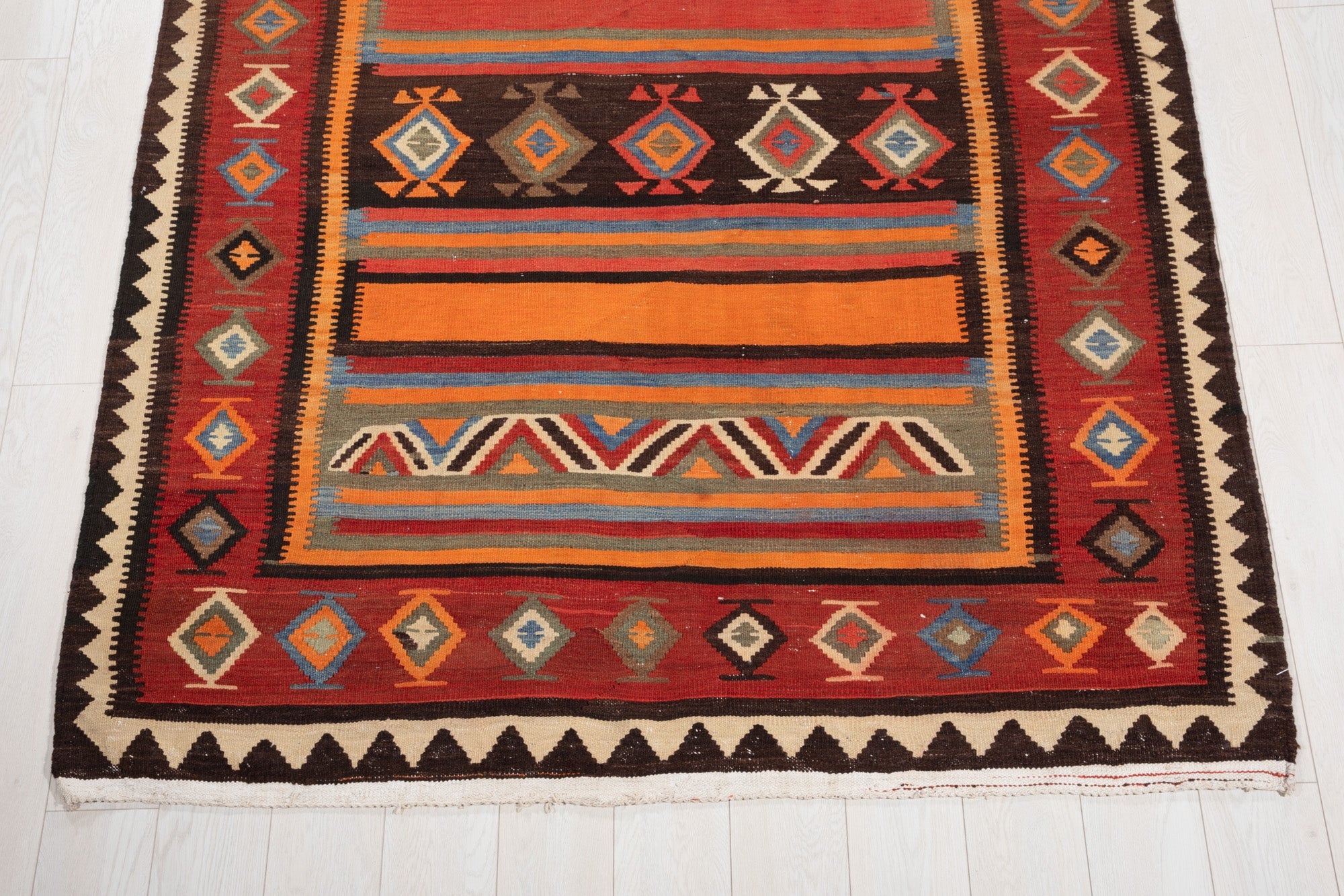One end of the kilim runner showing the zigzag band and diamond border pattern.