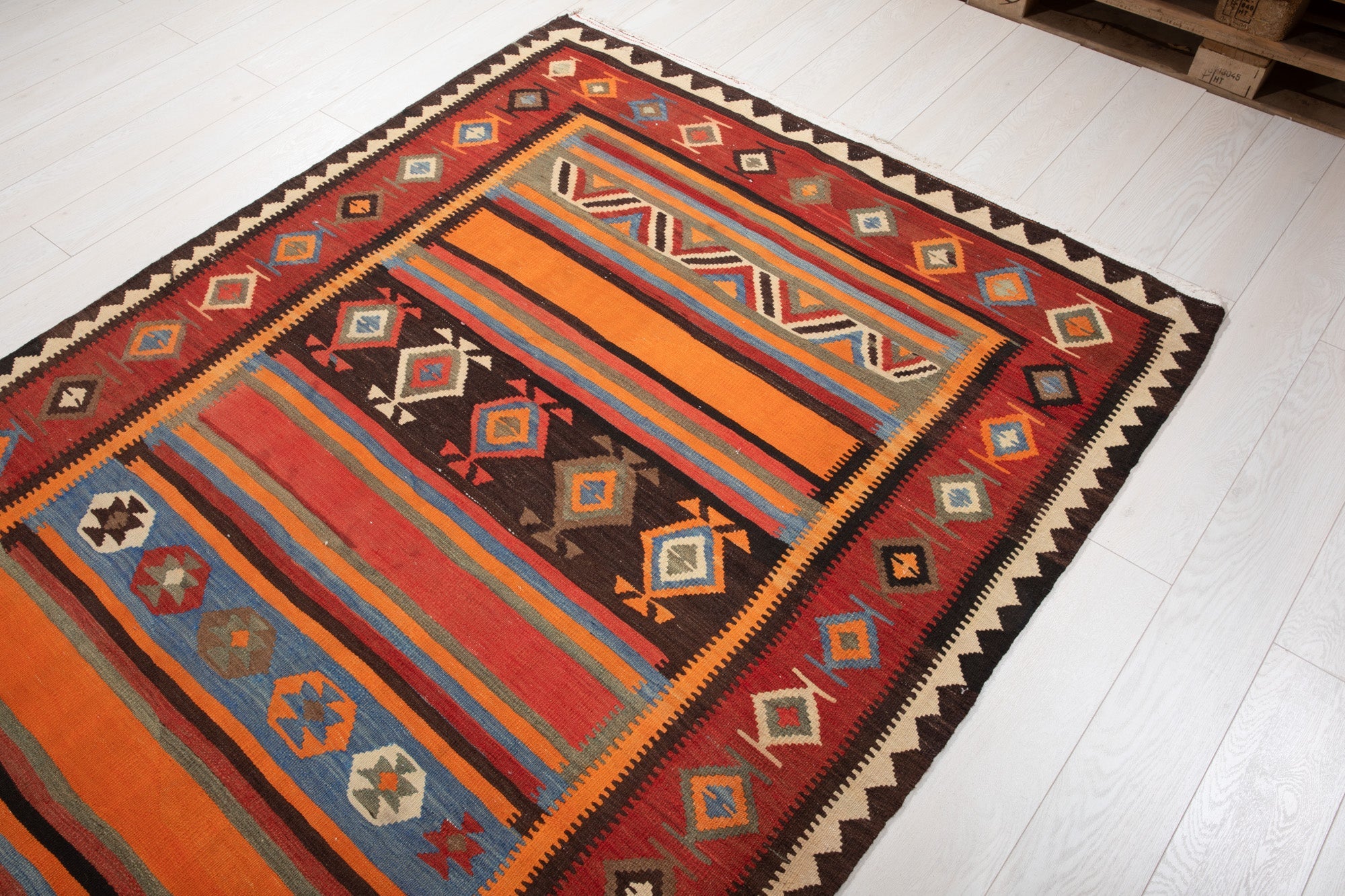 Warehouse angle shot of the kilim's striped pattern with pallets in the background.