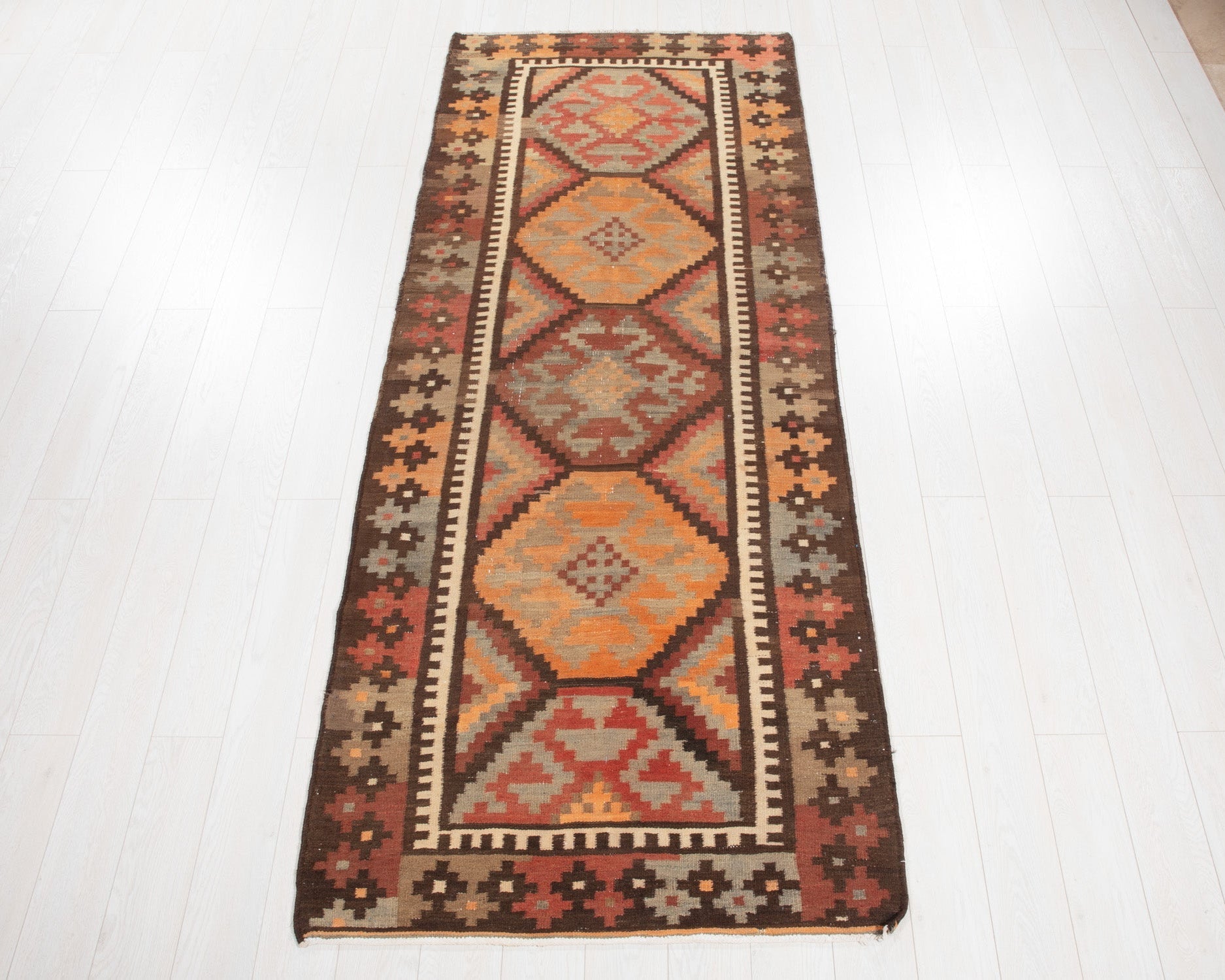 Full view of the antique Persian kilim runner in rustic orange geometric diamonds.