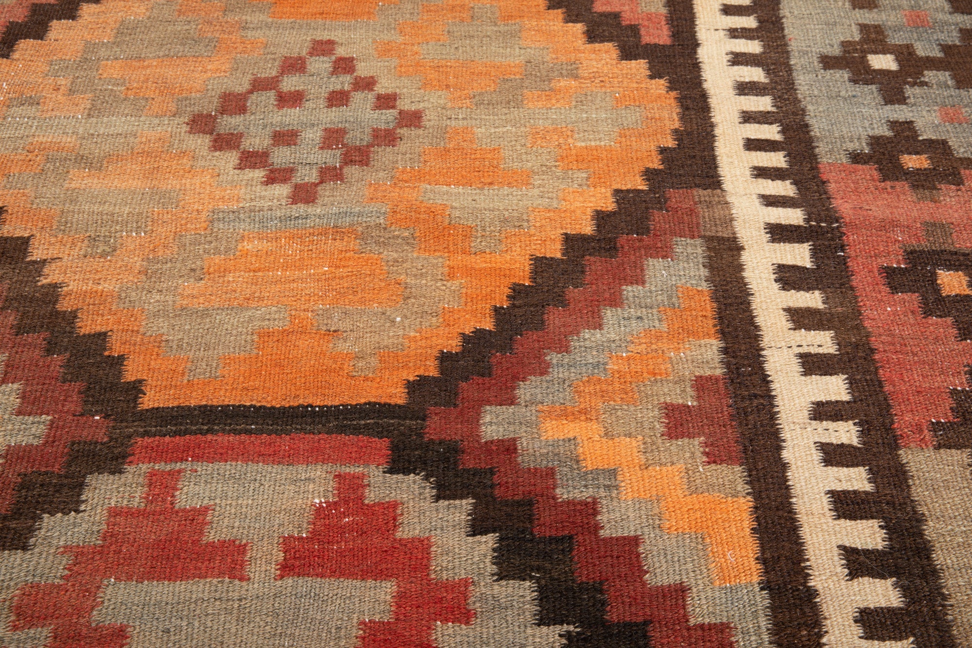 Close-up of the handwoven wool kilim's diamond motif and rustic texture.