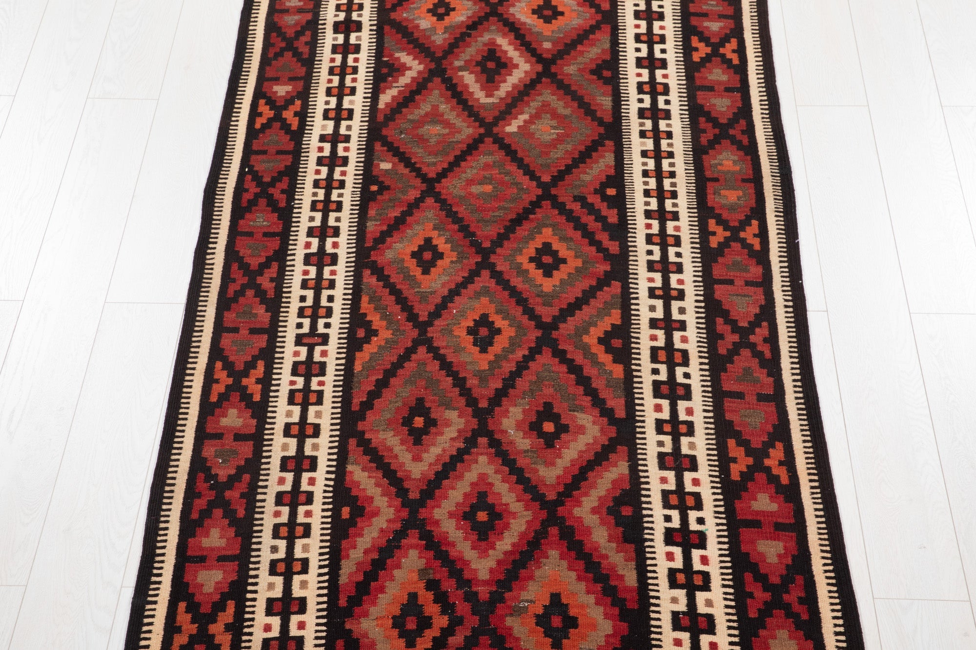 Top-down view of the kilim runner's diamond lattice pattern and diamond border.