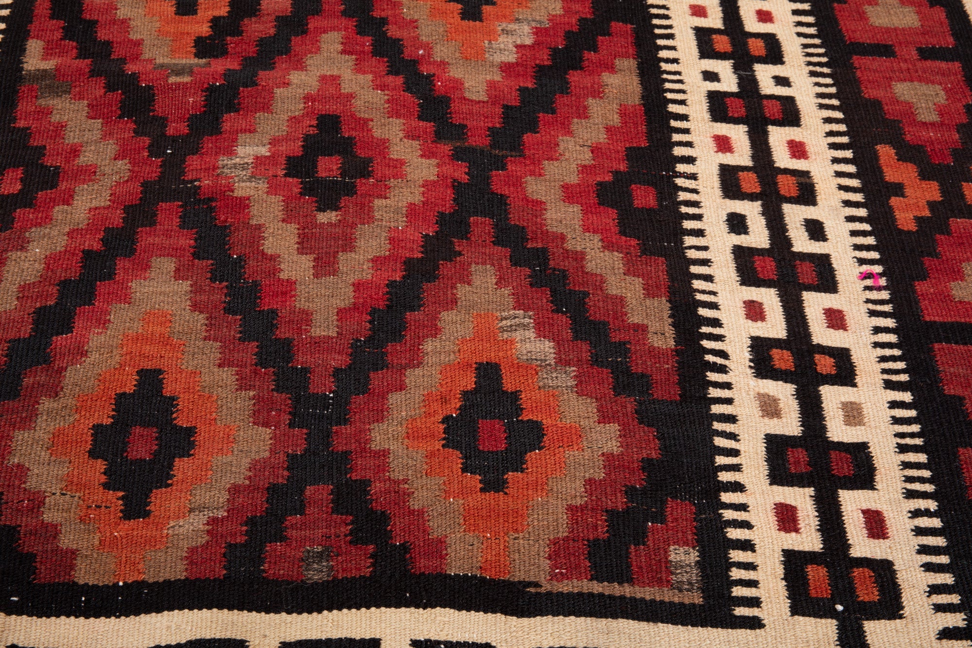 Warehouse angle shot of the kilim's diamond pattern and cream border stripe.