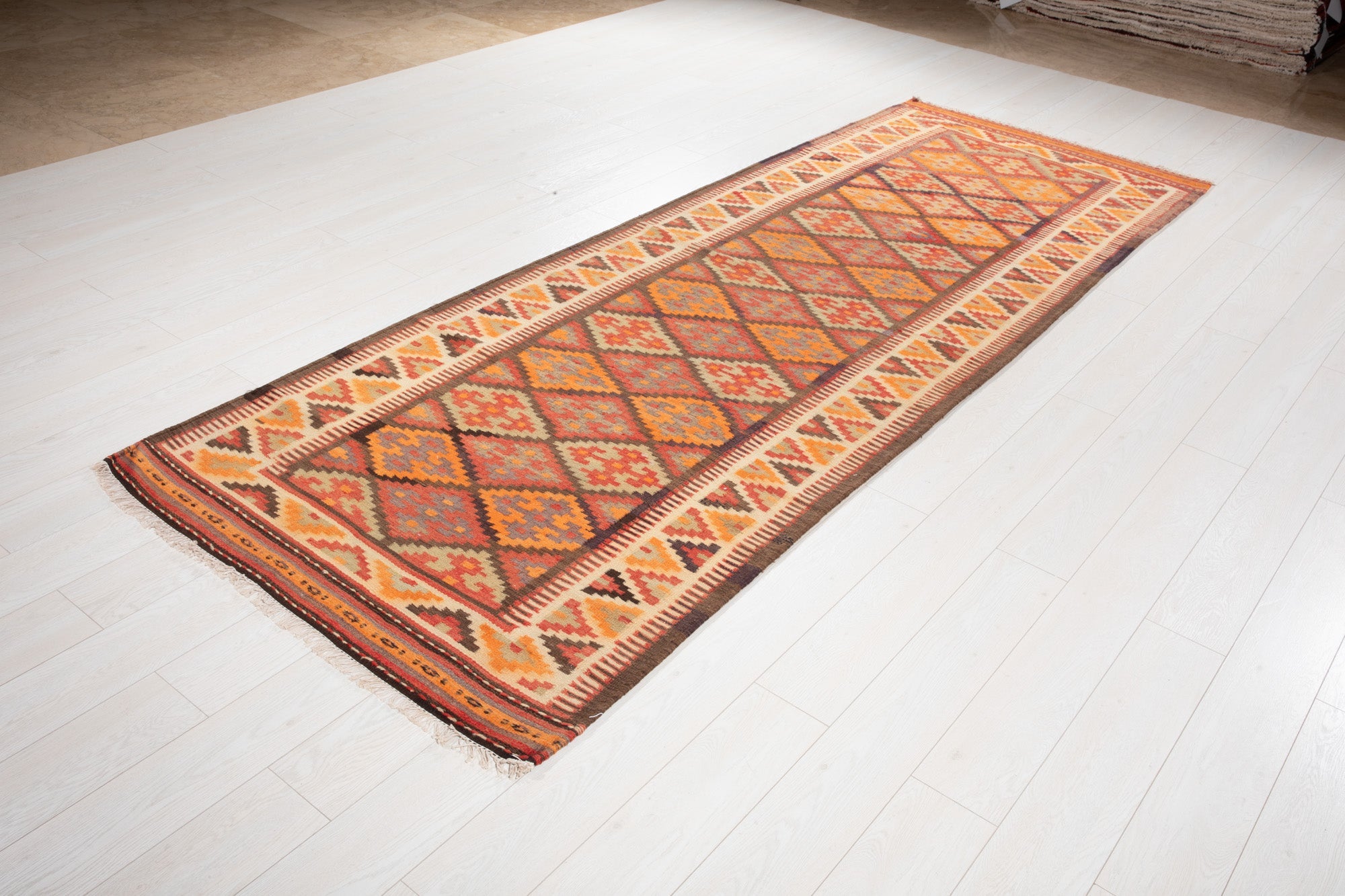 Angled view of the Persian kilim runner's diamond pattern in the showroom.