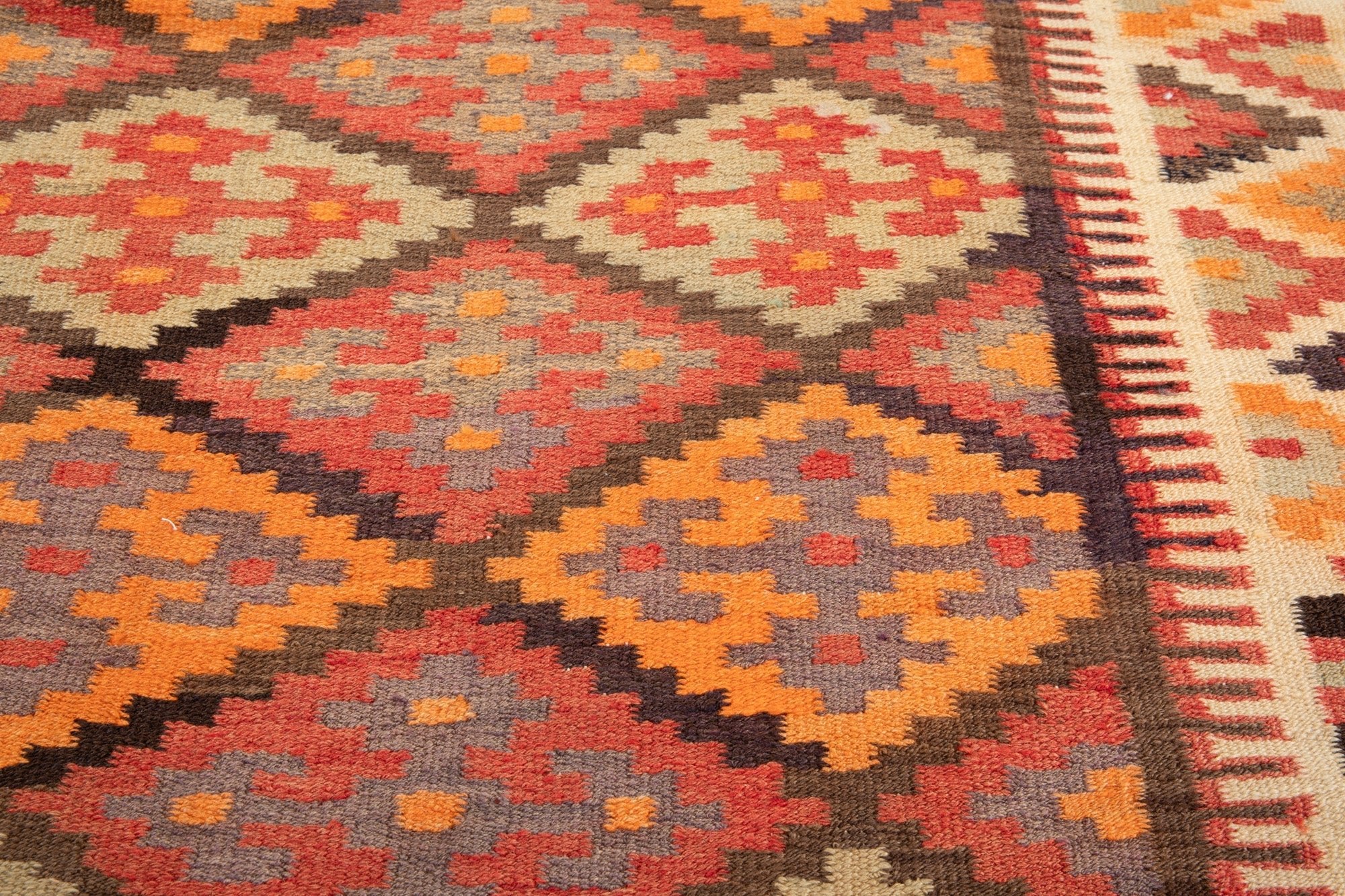 Extreme close-up of the handwoven wool kilim's diamond weave texture.