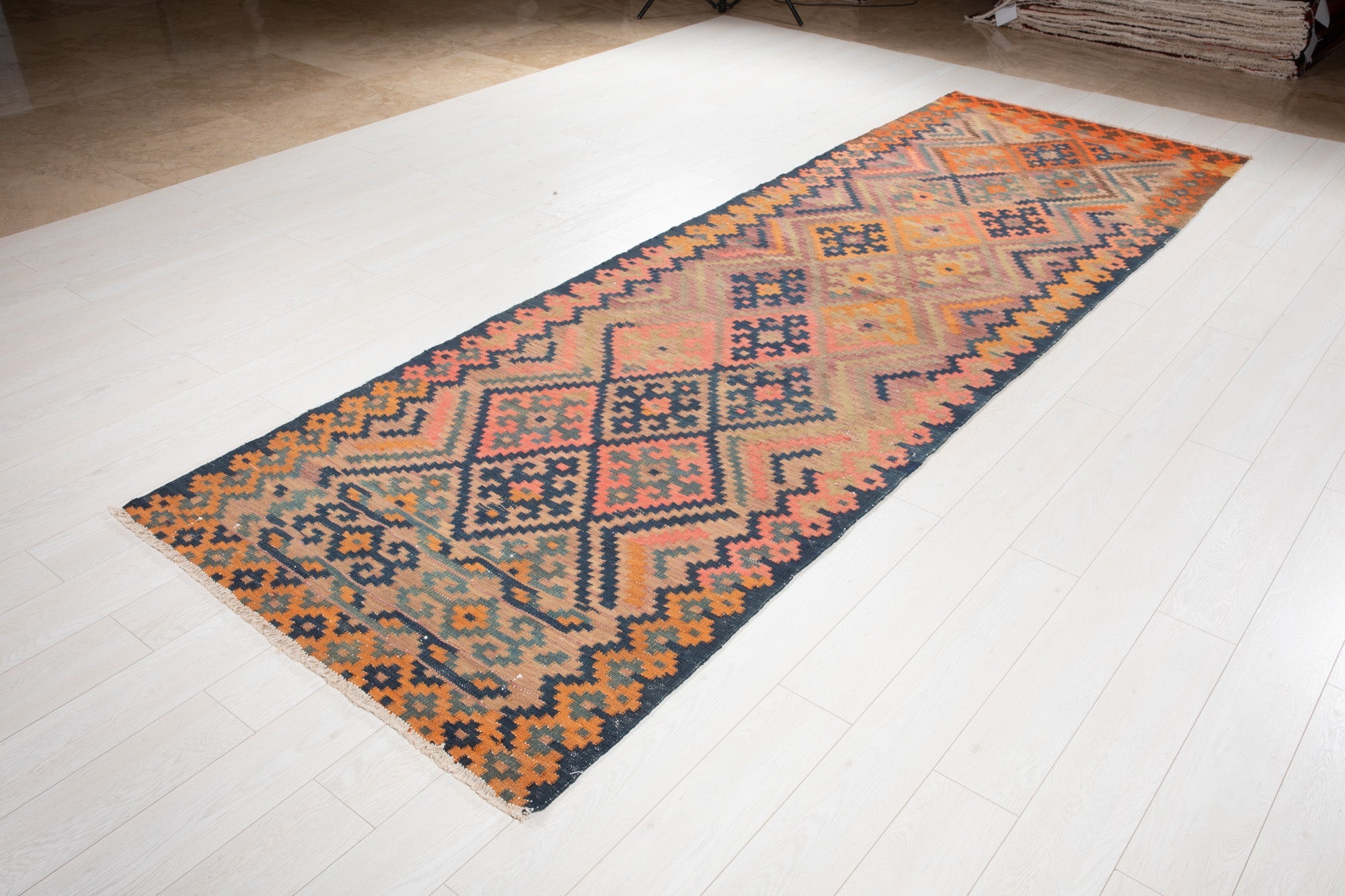 Angled view of the antique Persian runner's navy and orange diamond pattern.