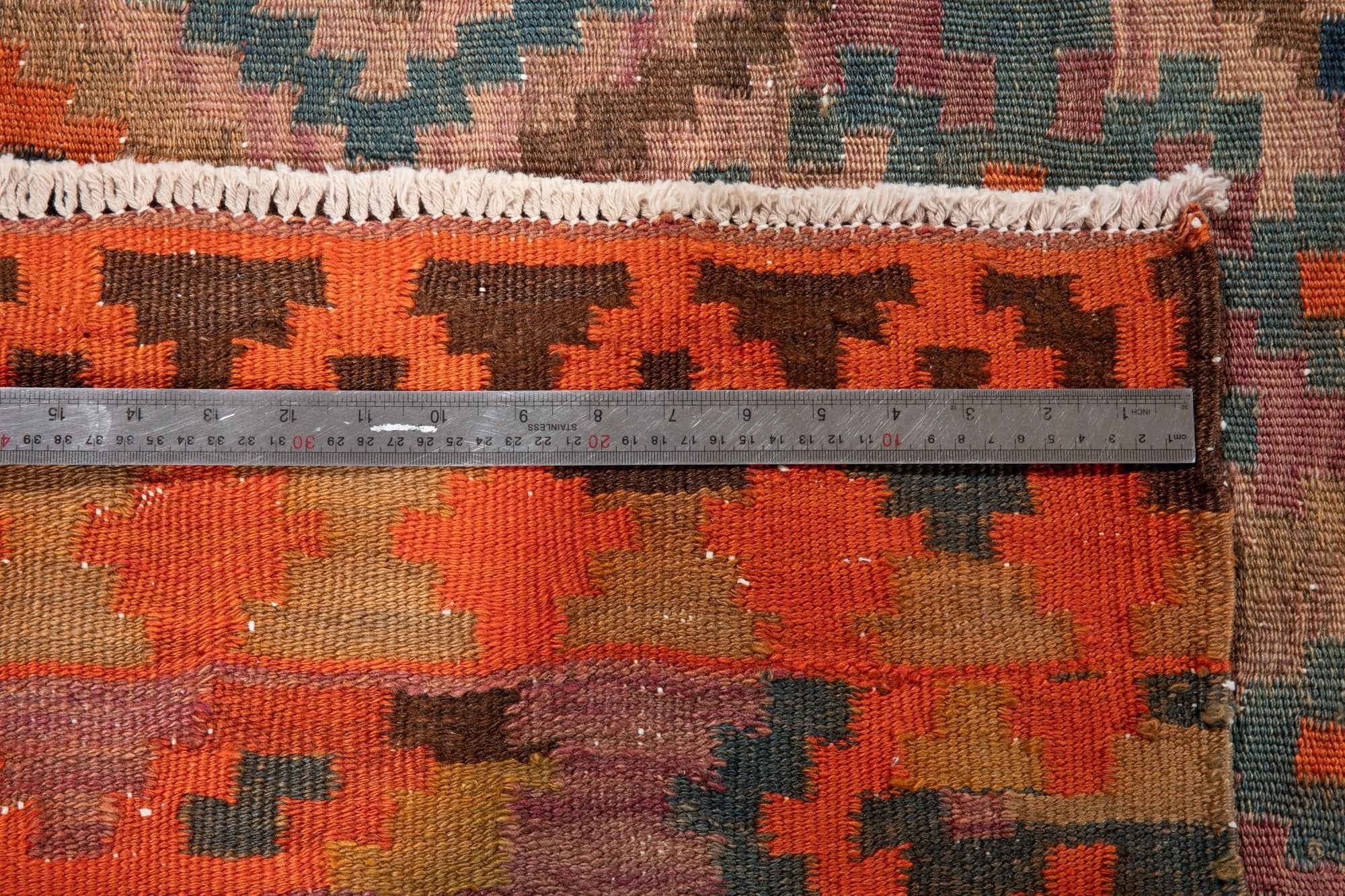 Ruler measuring the runner's bright orange border next to its fringe.