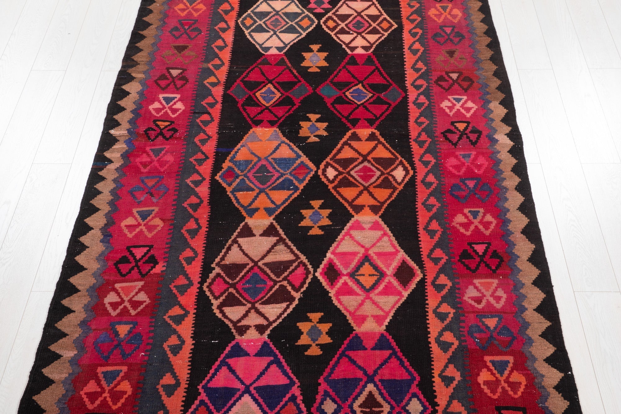 Top-down view of the kilim's diamond medallions on a black field.