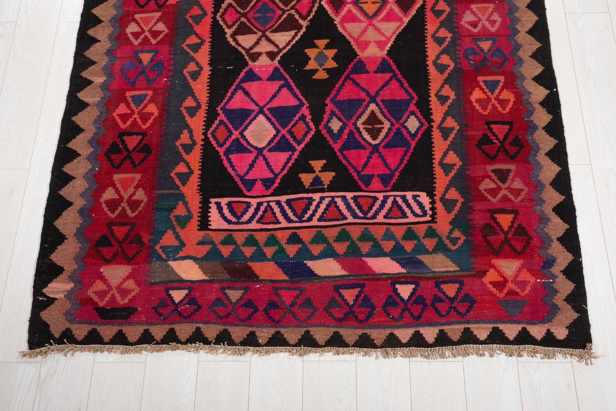 One end of the rug showing two diamond medallions and a colorful striped band.