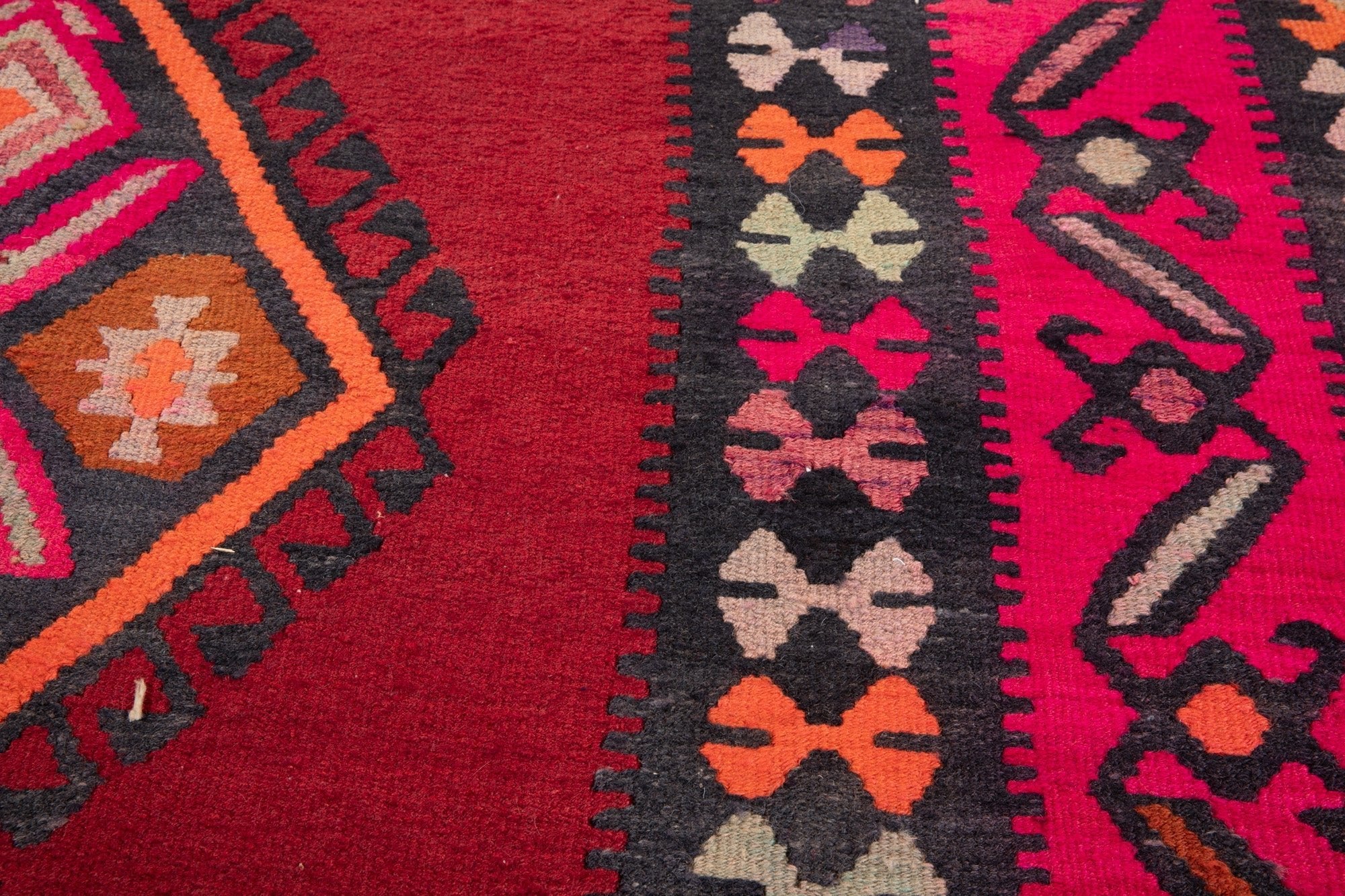 Close-up of the handwoven wool kilim's diamond medallion and bow-tie border motifs.