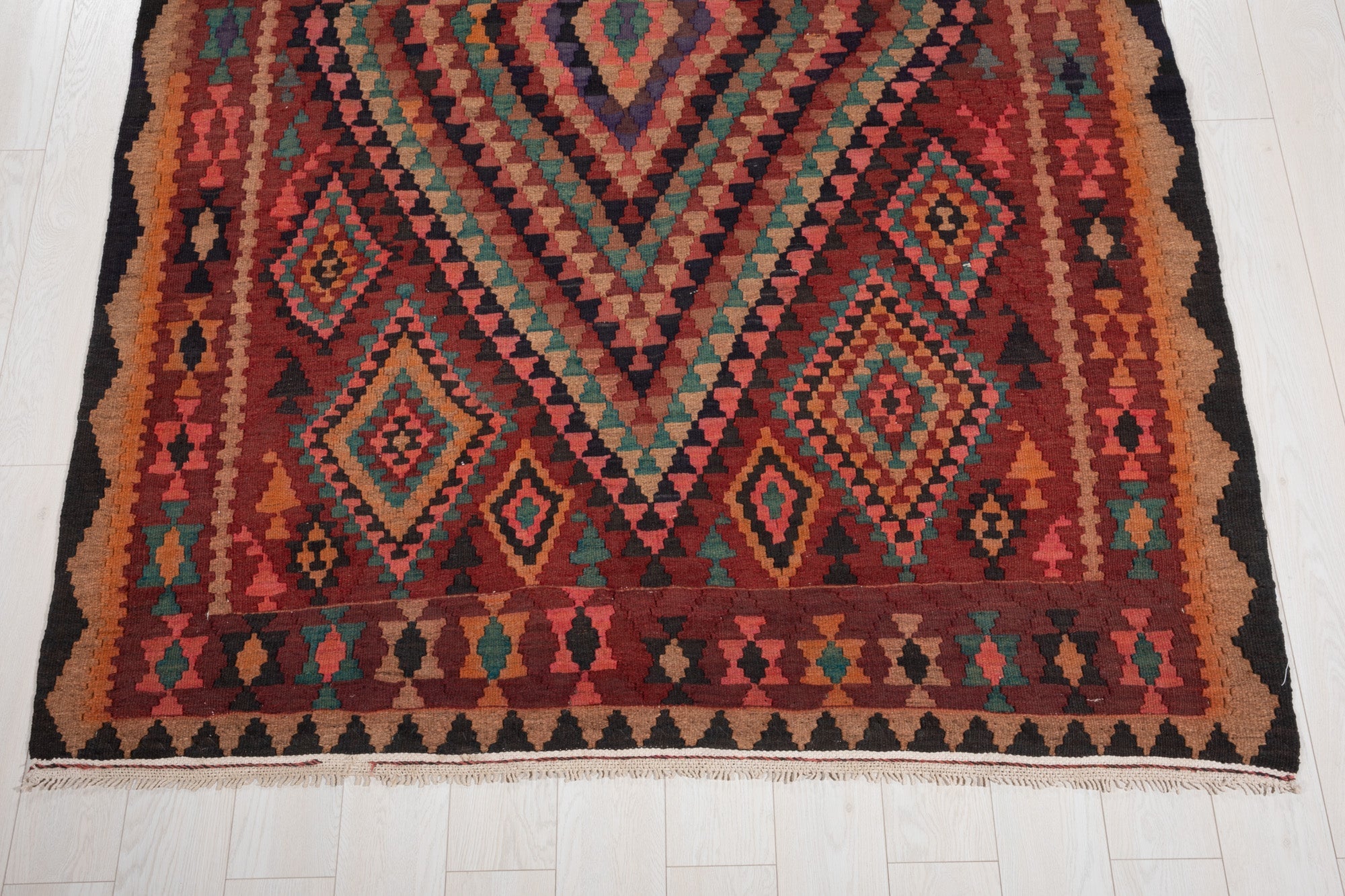 One end of the rug showing its fringe and colorful diamond border.