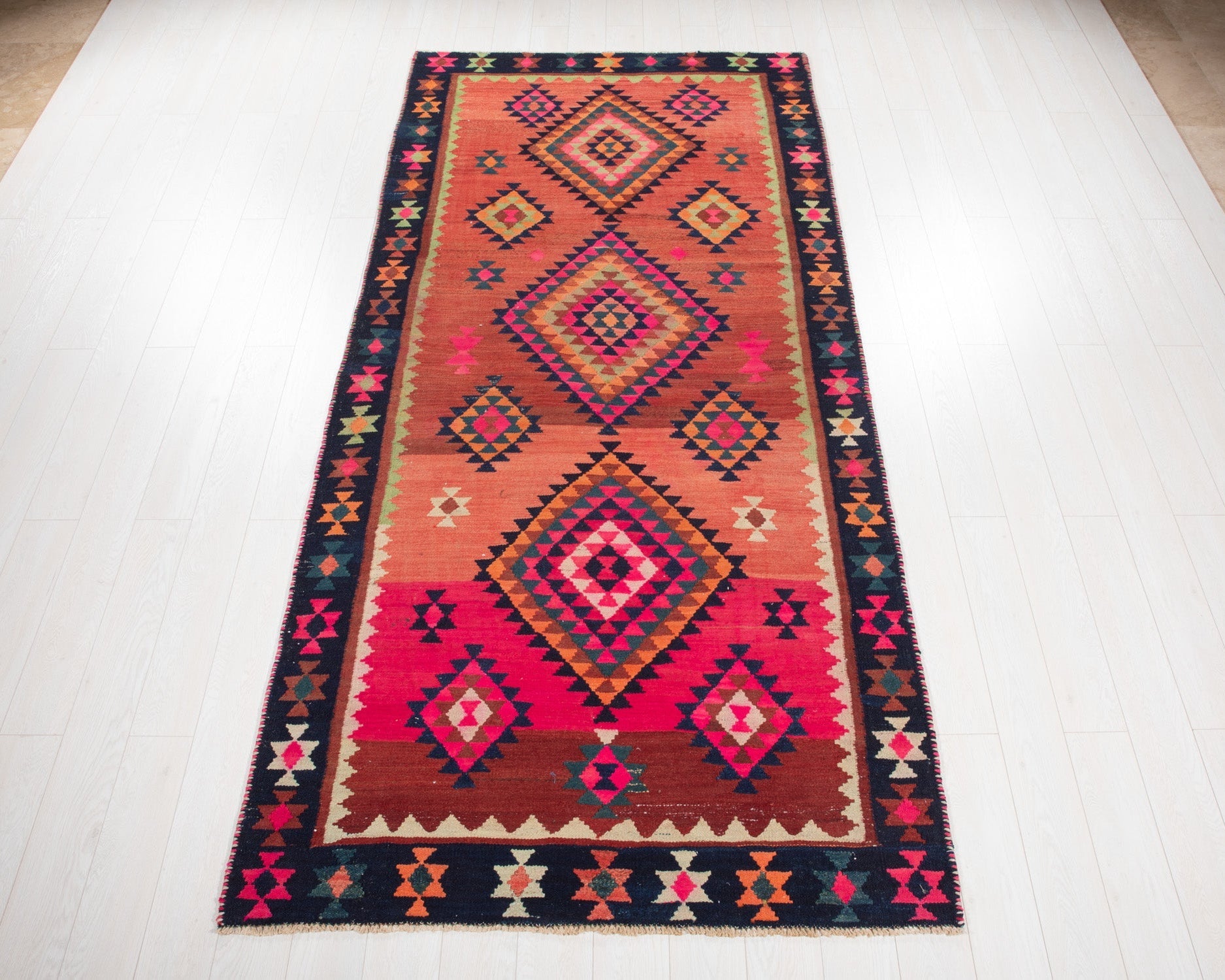 Full view of the vintage Shiraz Persian tribal kilim rug in red and pink diamond medallions.