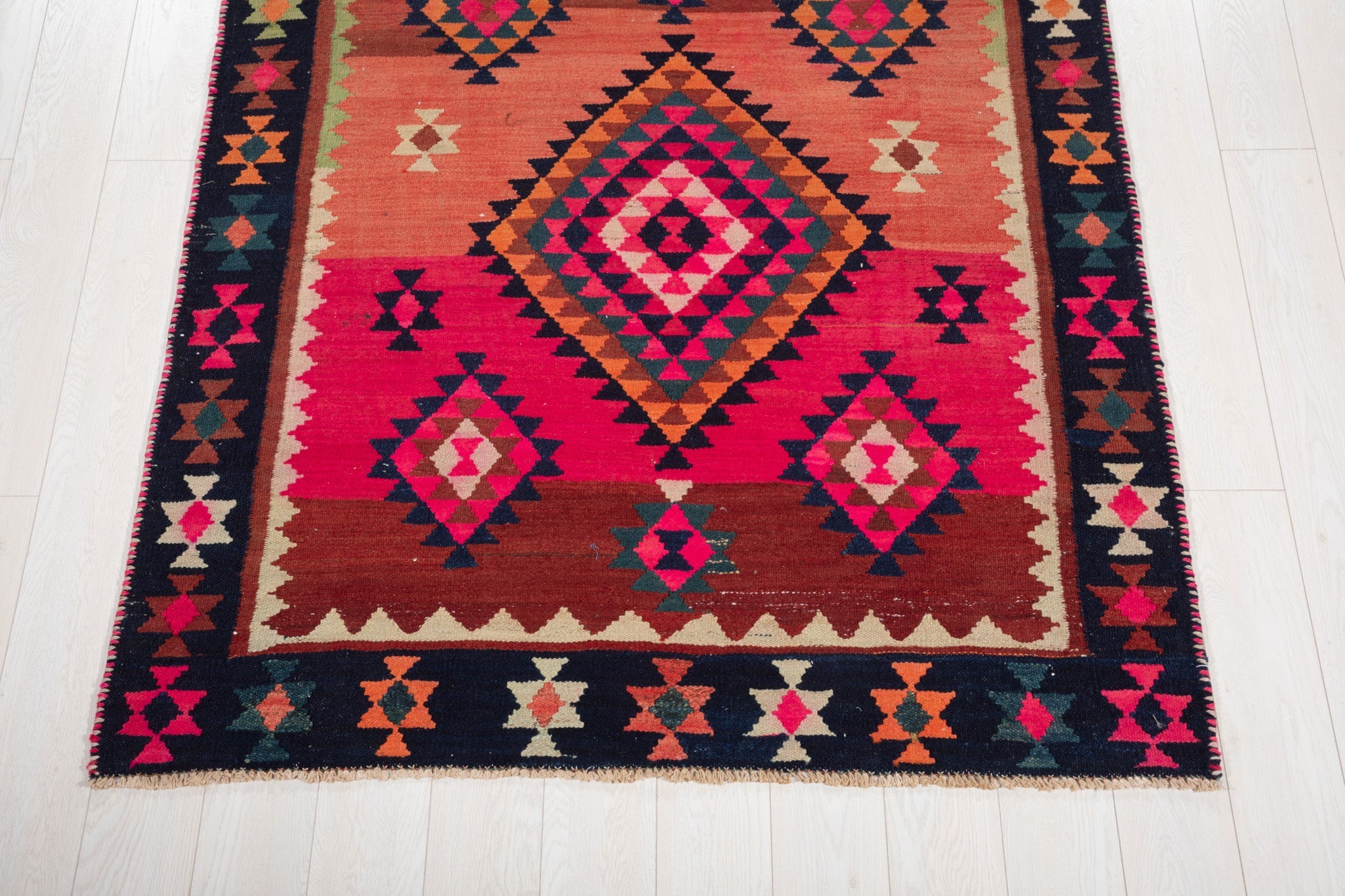 One end of the rug showing its fringe and diamond border pattern.