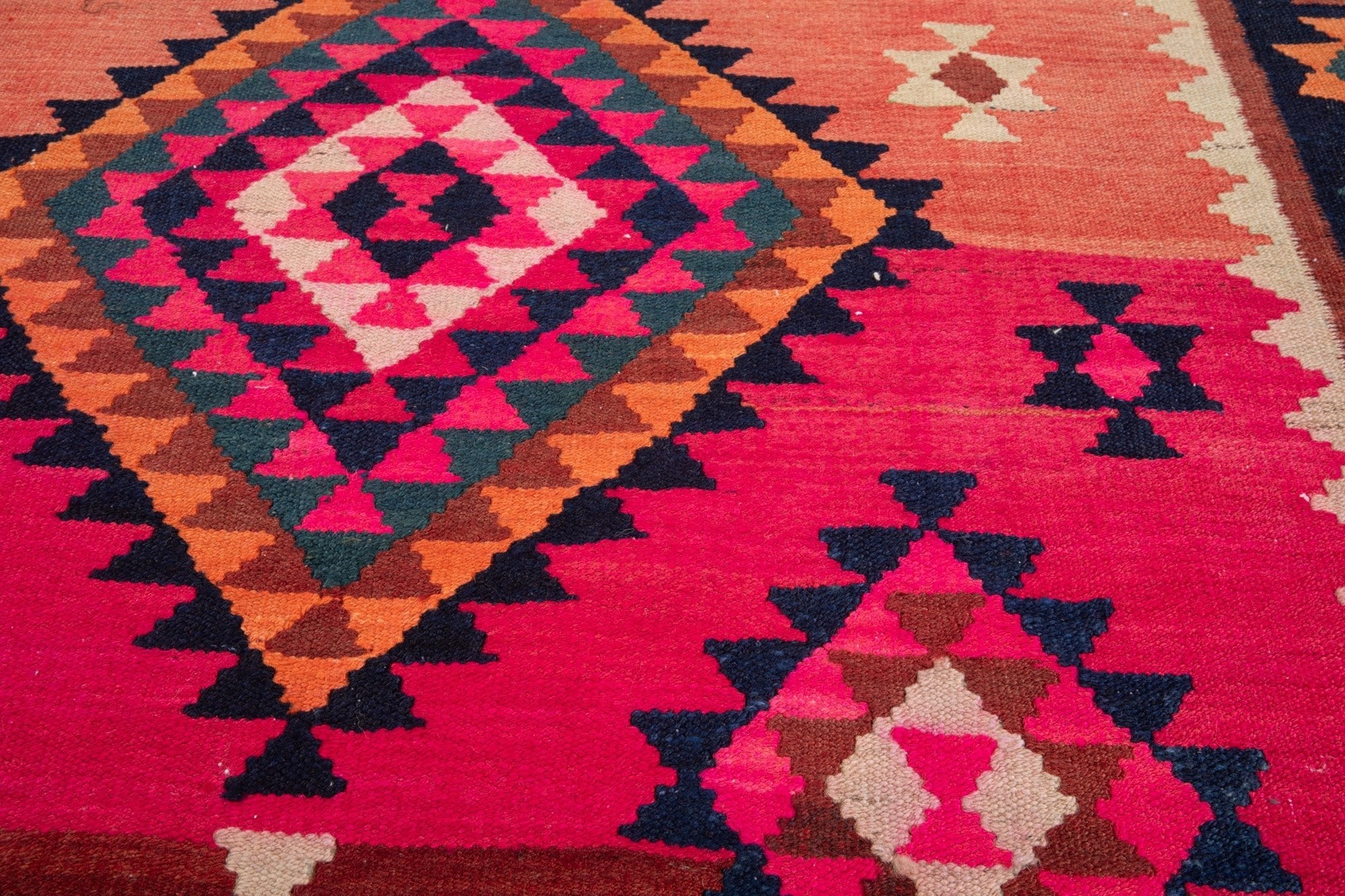 Close-up of the handwoven wool kilim's diamond medallion on a hot pink field.