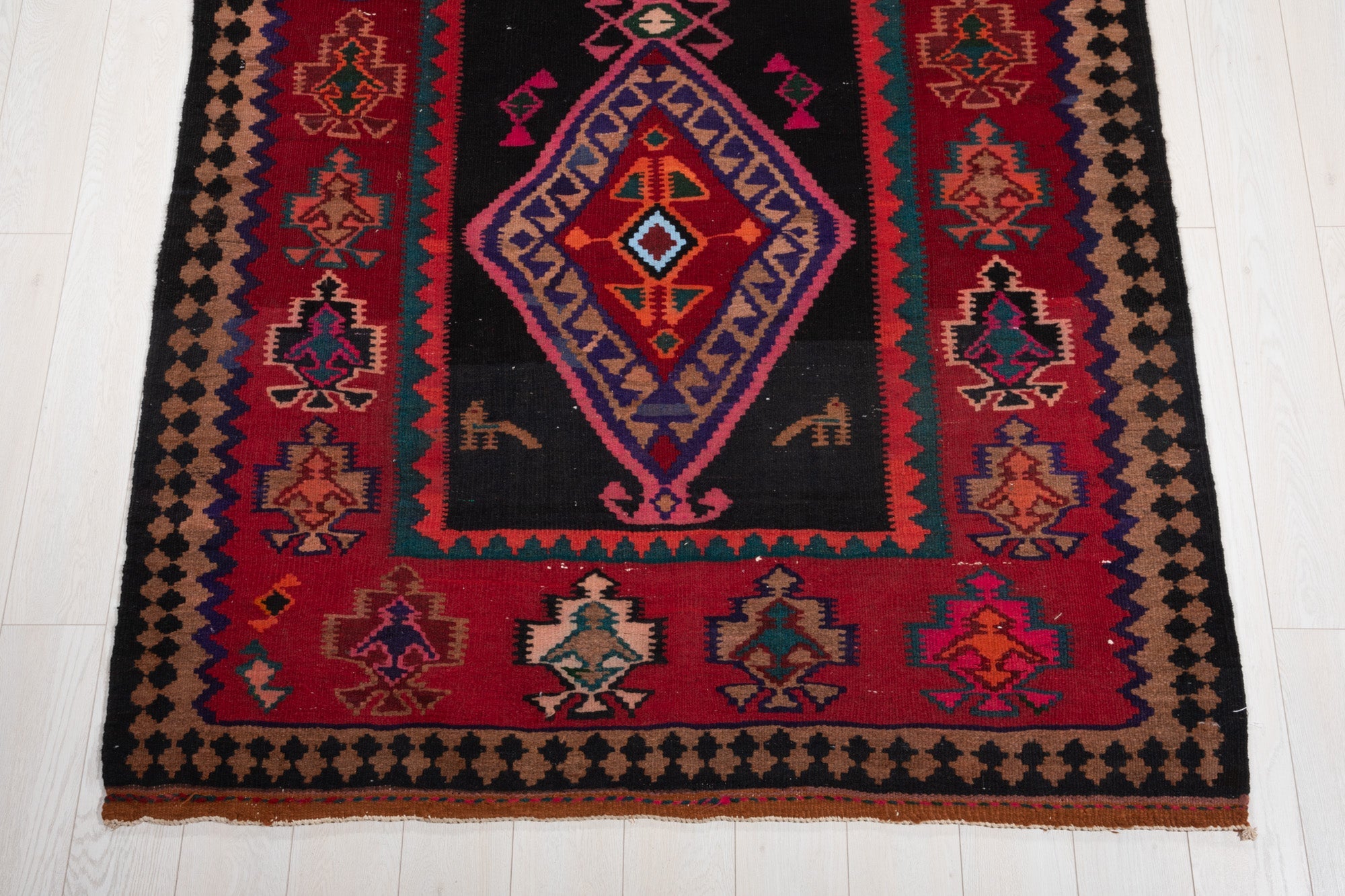 One end of the rug showing its diamond medallion with small animal figure motifs.