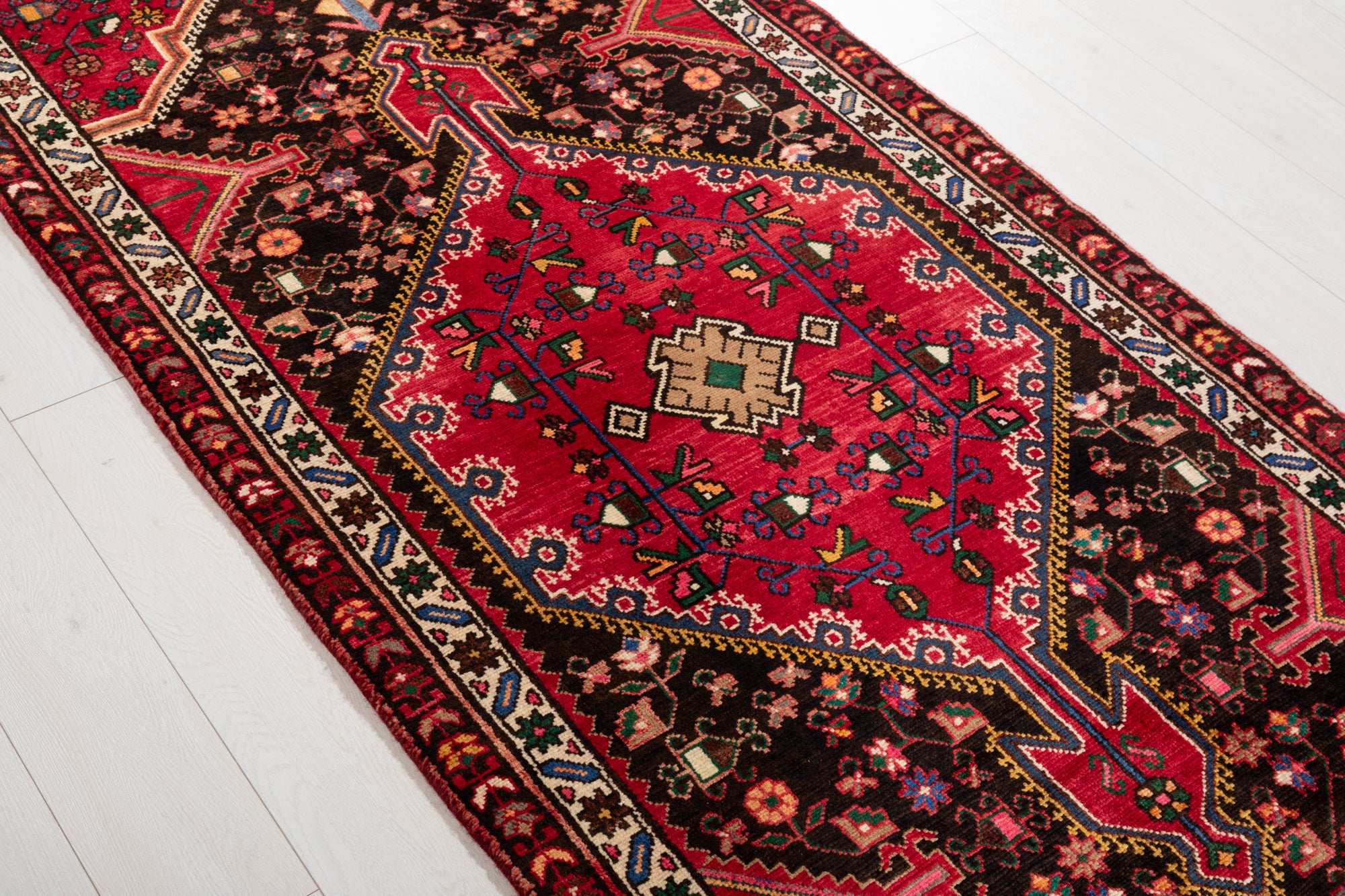Side angle of Hand-Knotted Vintage Wool Runner Rug – 9' 3" x 3' 5" showing its vibrant red and black color palette and fine craftsmanship.