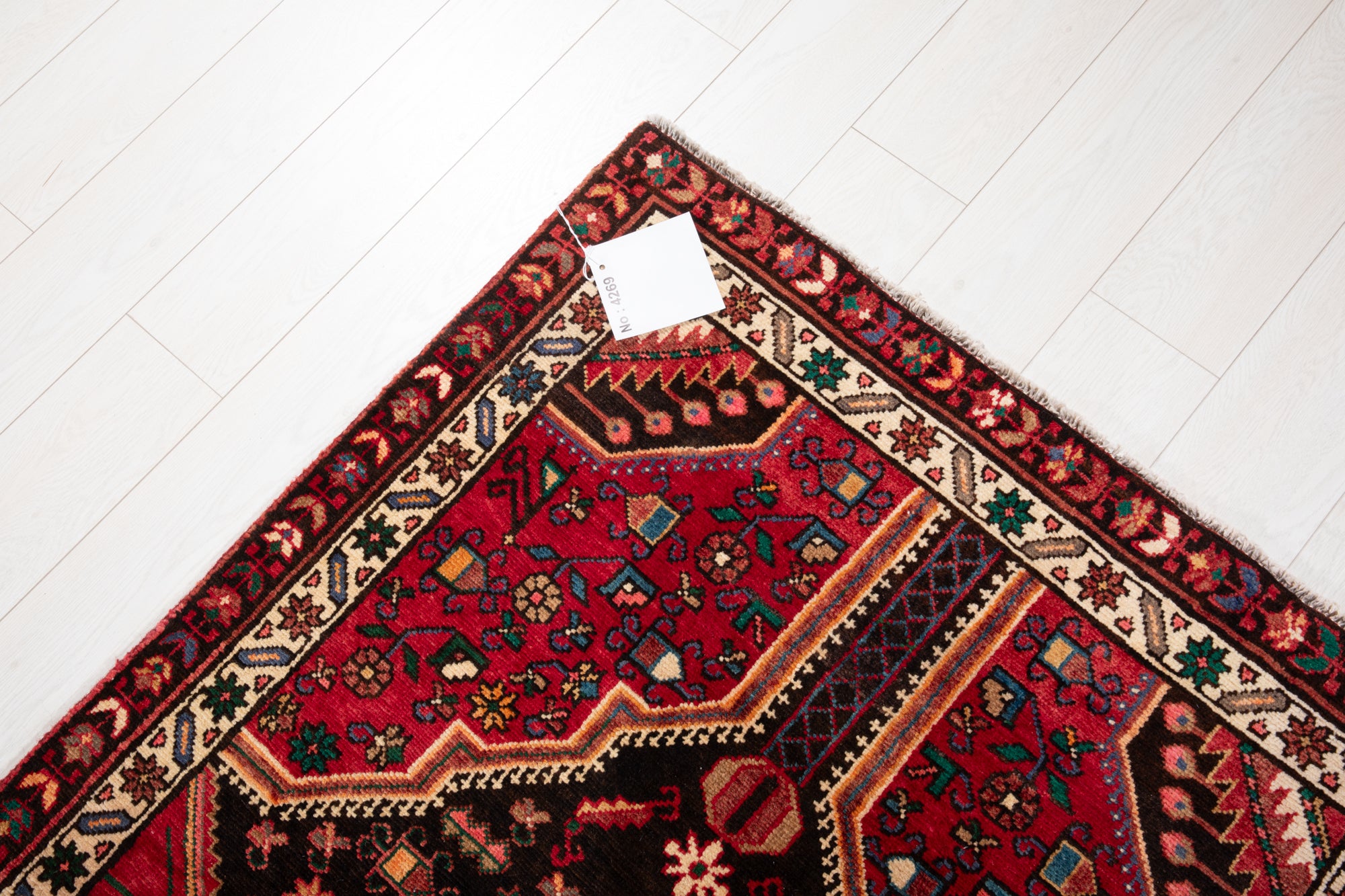 Corner of Hand-Knotted Vintage Wool Runner Rug – 9' 3" x 3' 5" with product tag, showing detailed border and vibrant red tones.