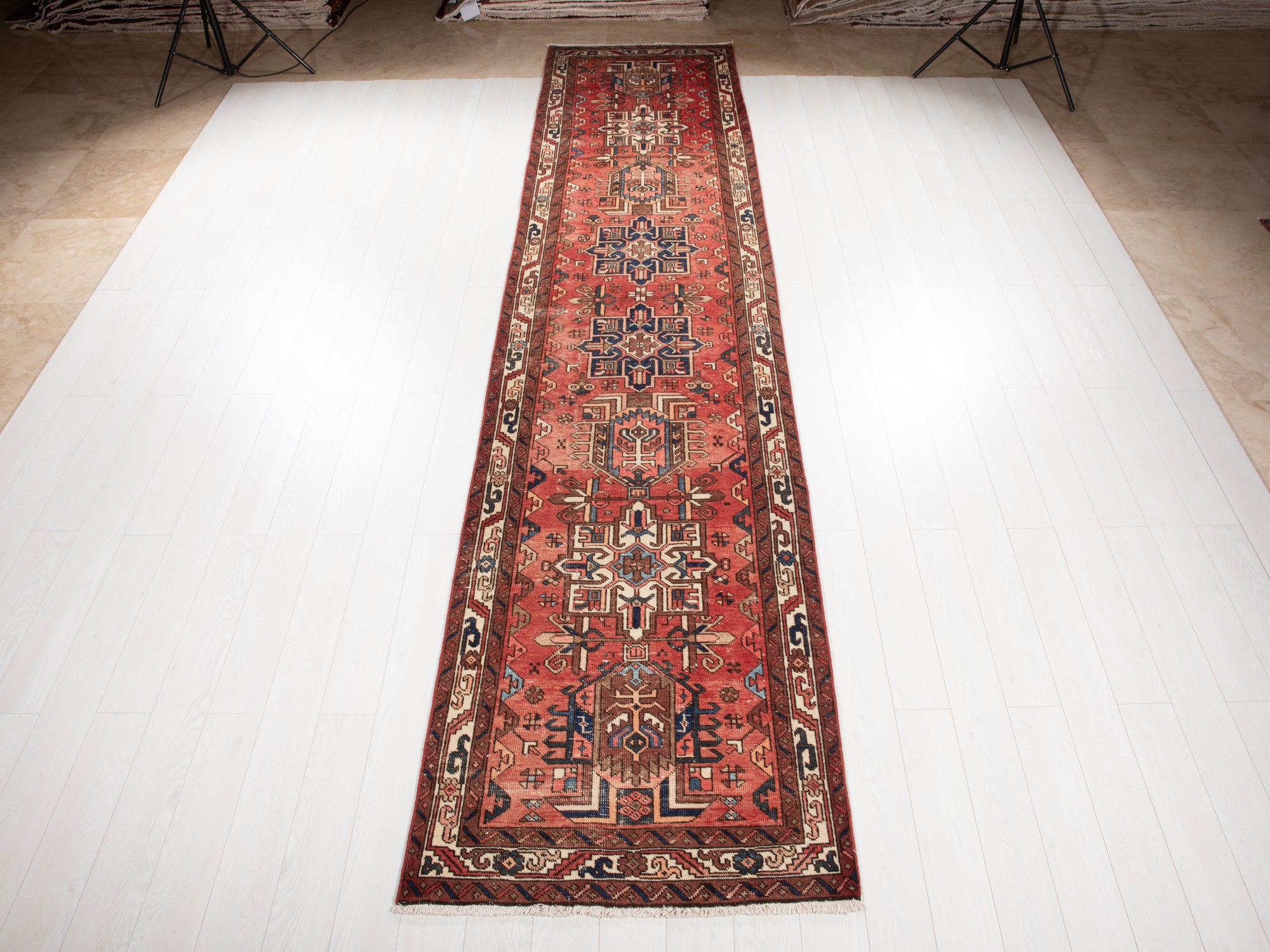 Hand-Knotted Antique Wool Runner Rug – 14' 9" x 3' 4" displayed fully on white wooden flooring, showcasing intricate tribal patterns in red and navy tones.