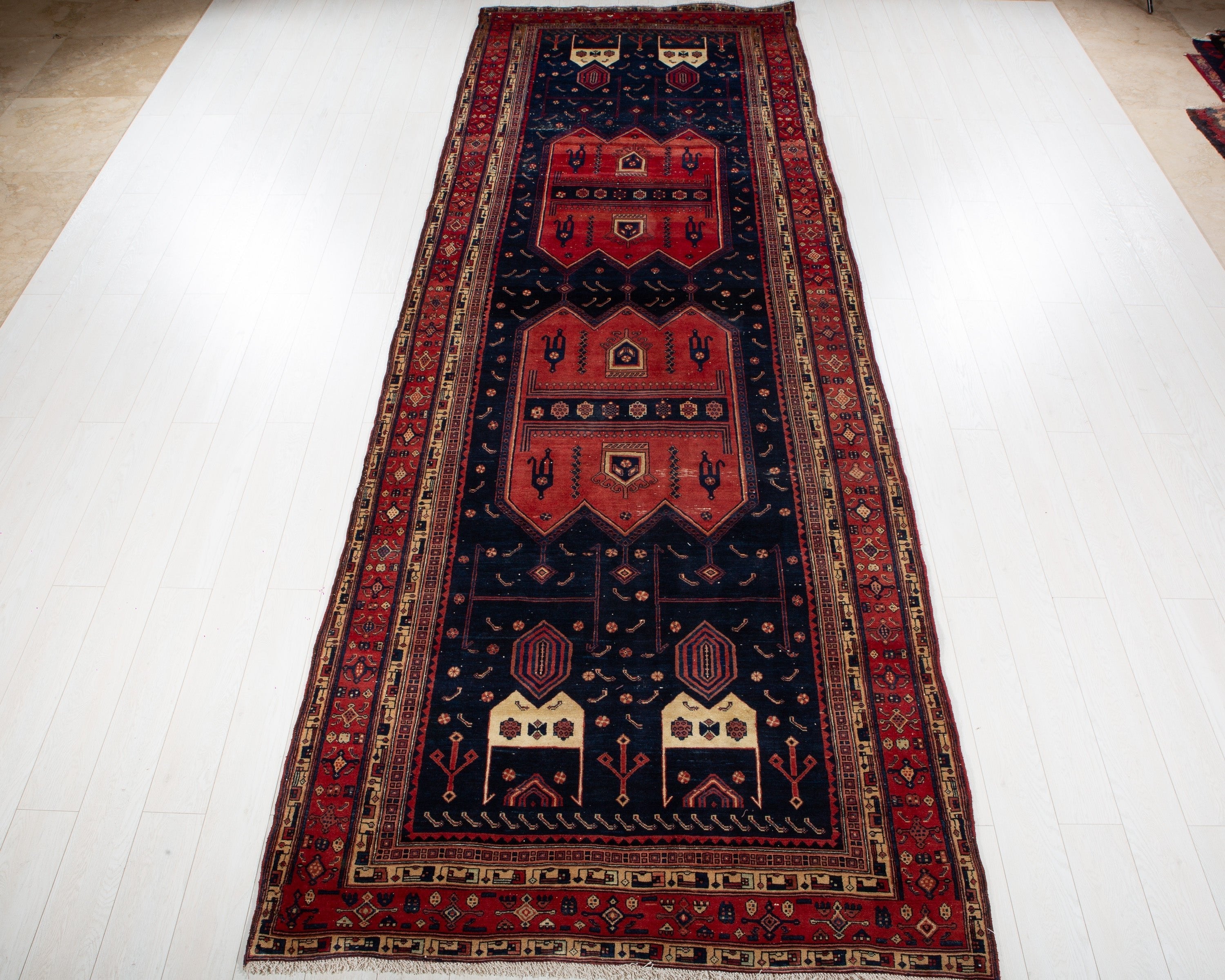 Full view of the red and navy Kurdish Persian tribal wool rug with nomadic medallion pattern.