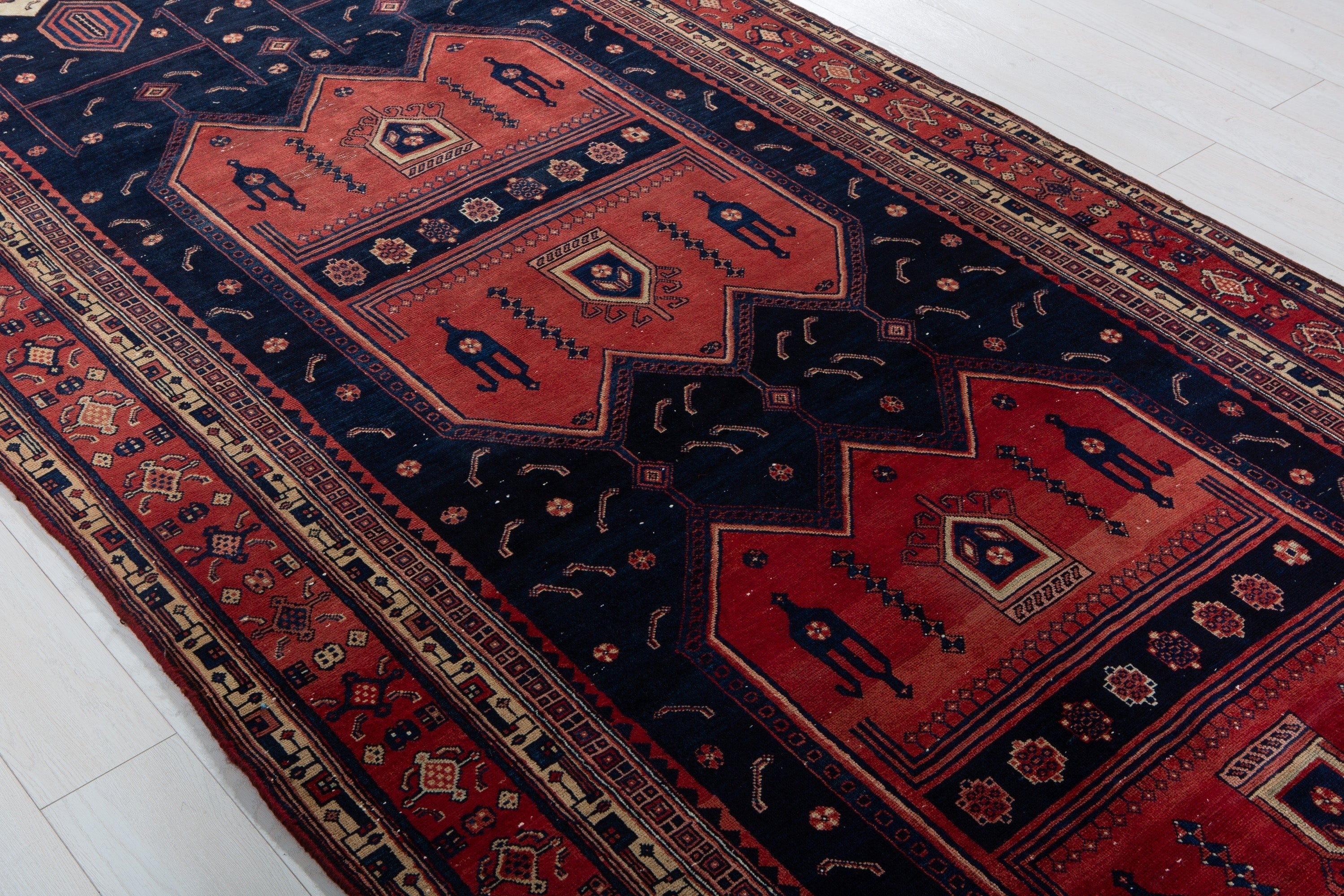 Diagonal angle of the rug showing repeating medallions with tribal diamond and figure motifs.