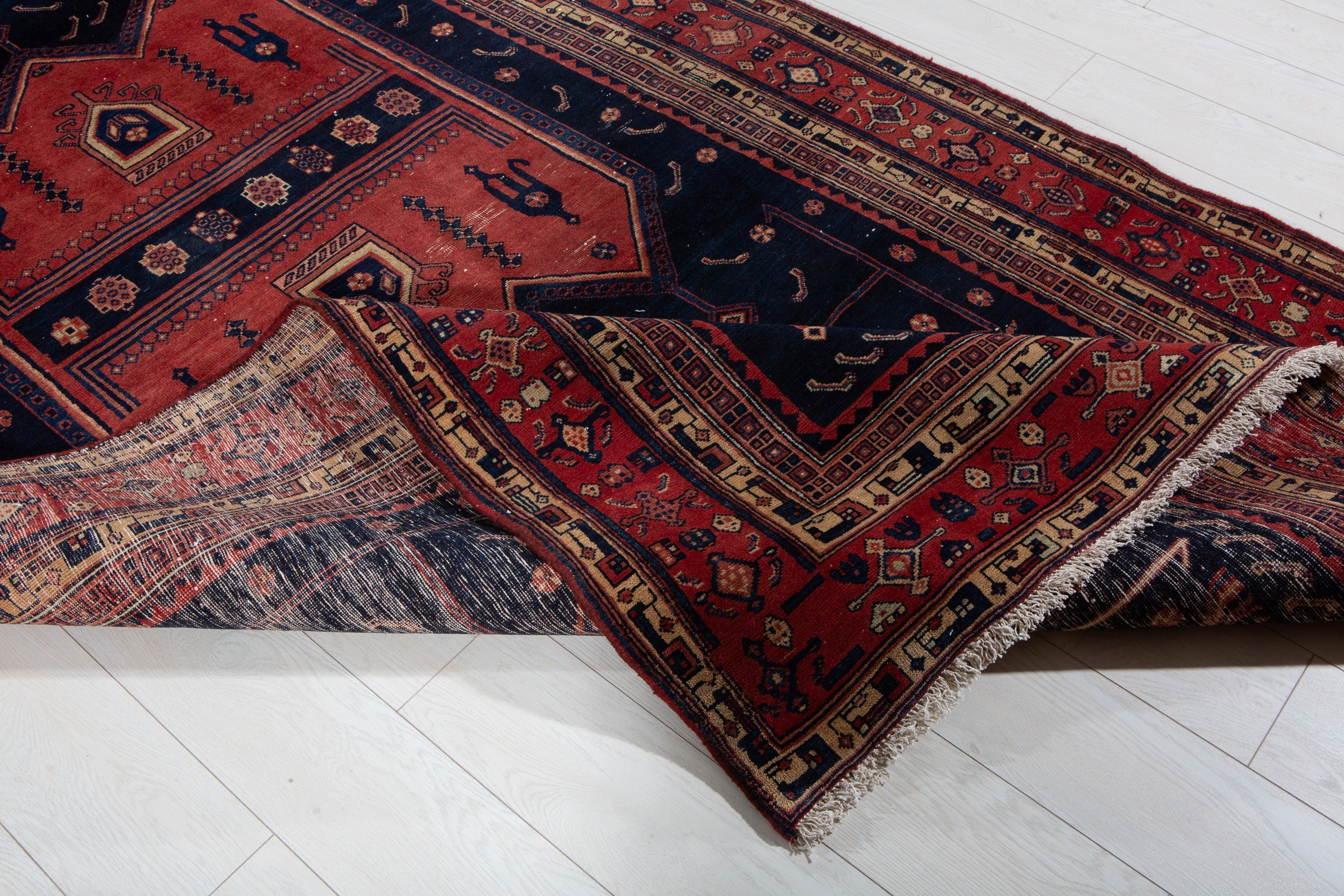 Corner of the rug folded back to reveal the woven foundation beneath the front pattern.