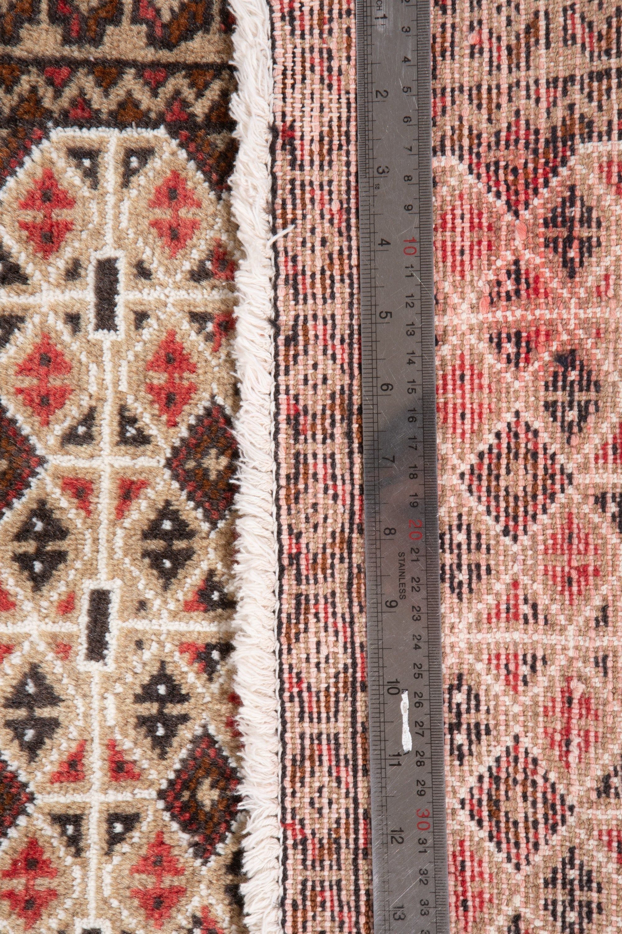 Measuring tape laid across the rug's width, showing the fringe and diamond pattern edge.