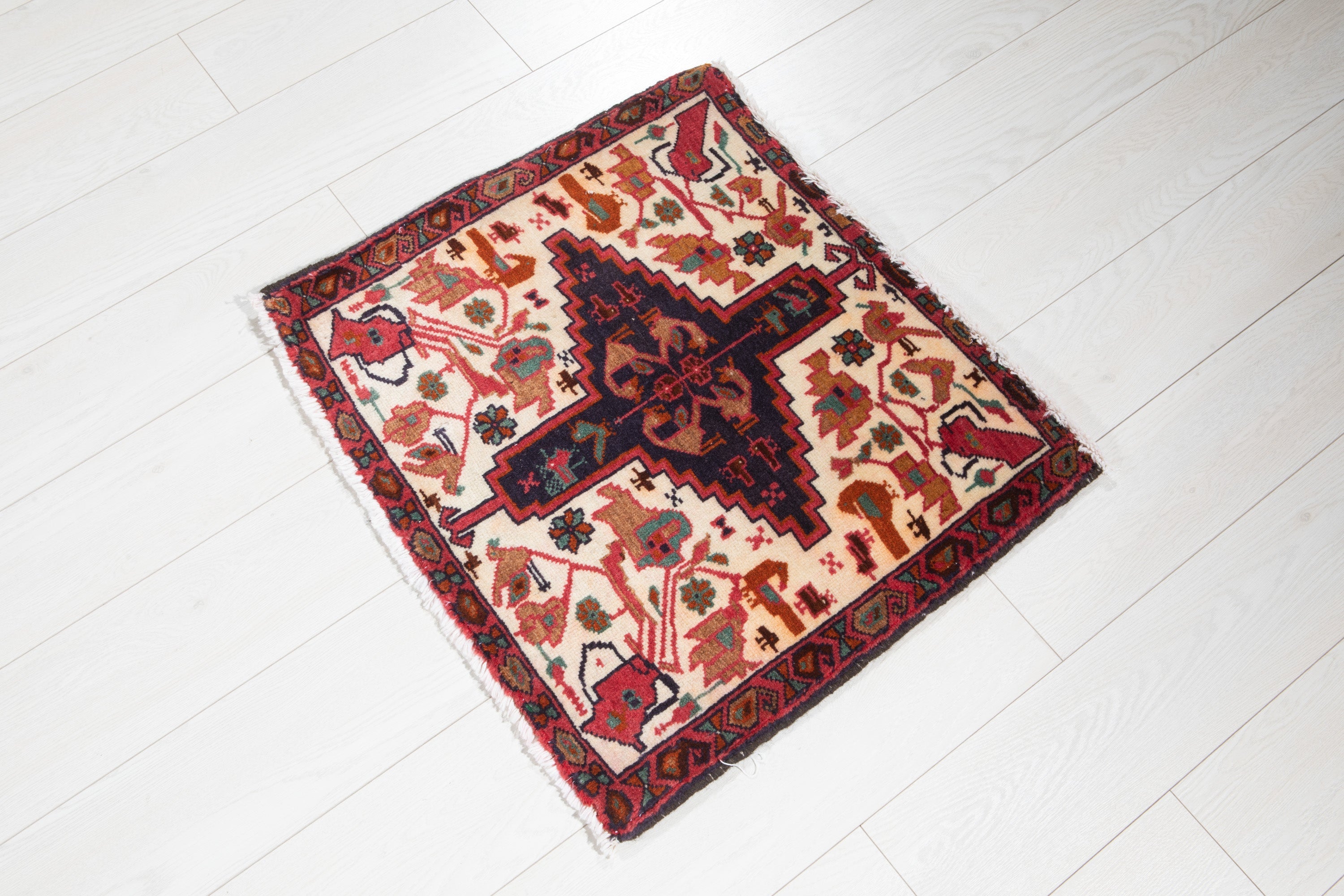 Angled view of the full Heriz rug on a wood floor, showing the medallion and corner motifs.