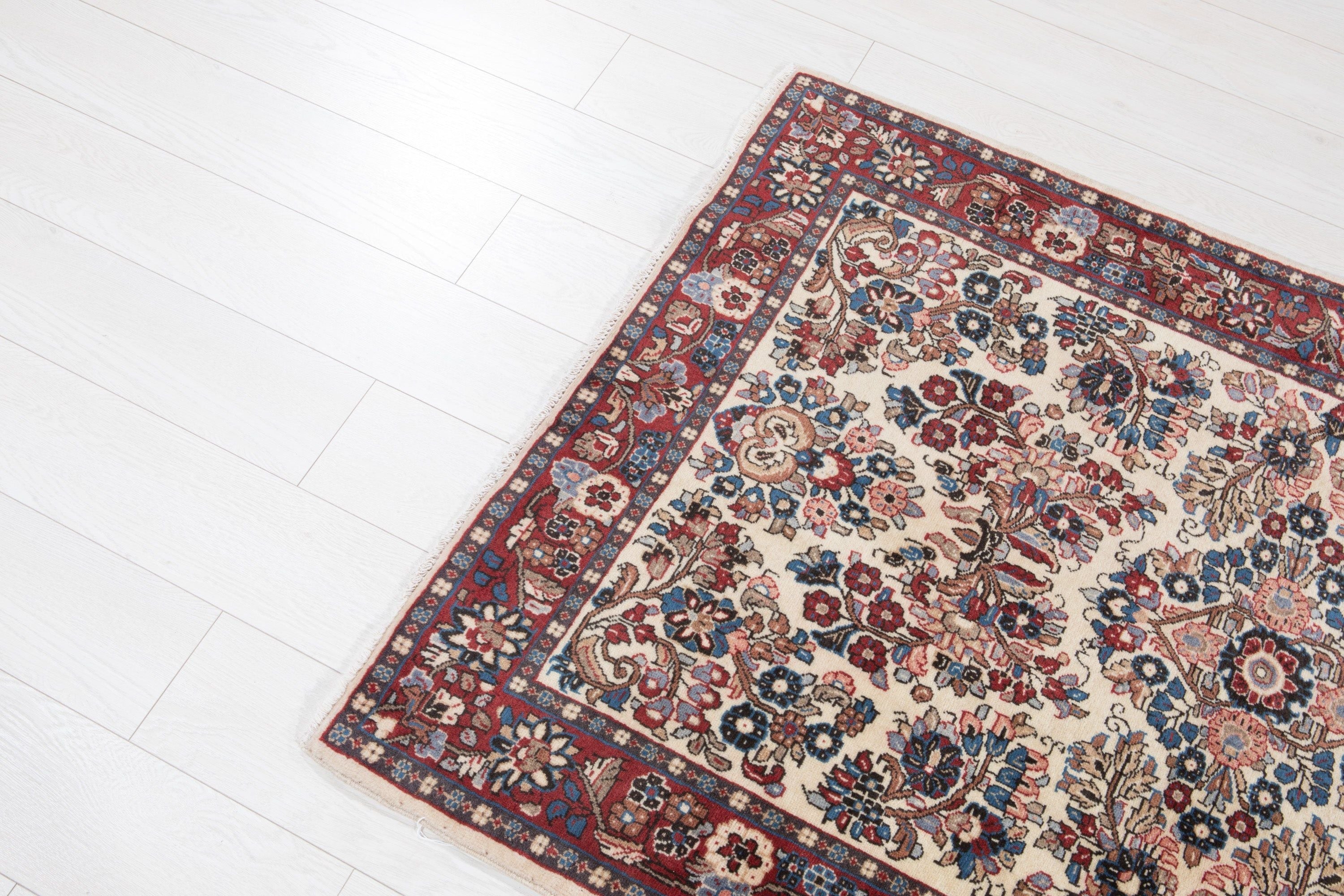 Corner-angle view of the rug highlighting the red border framing the floral field.