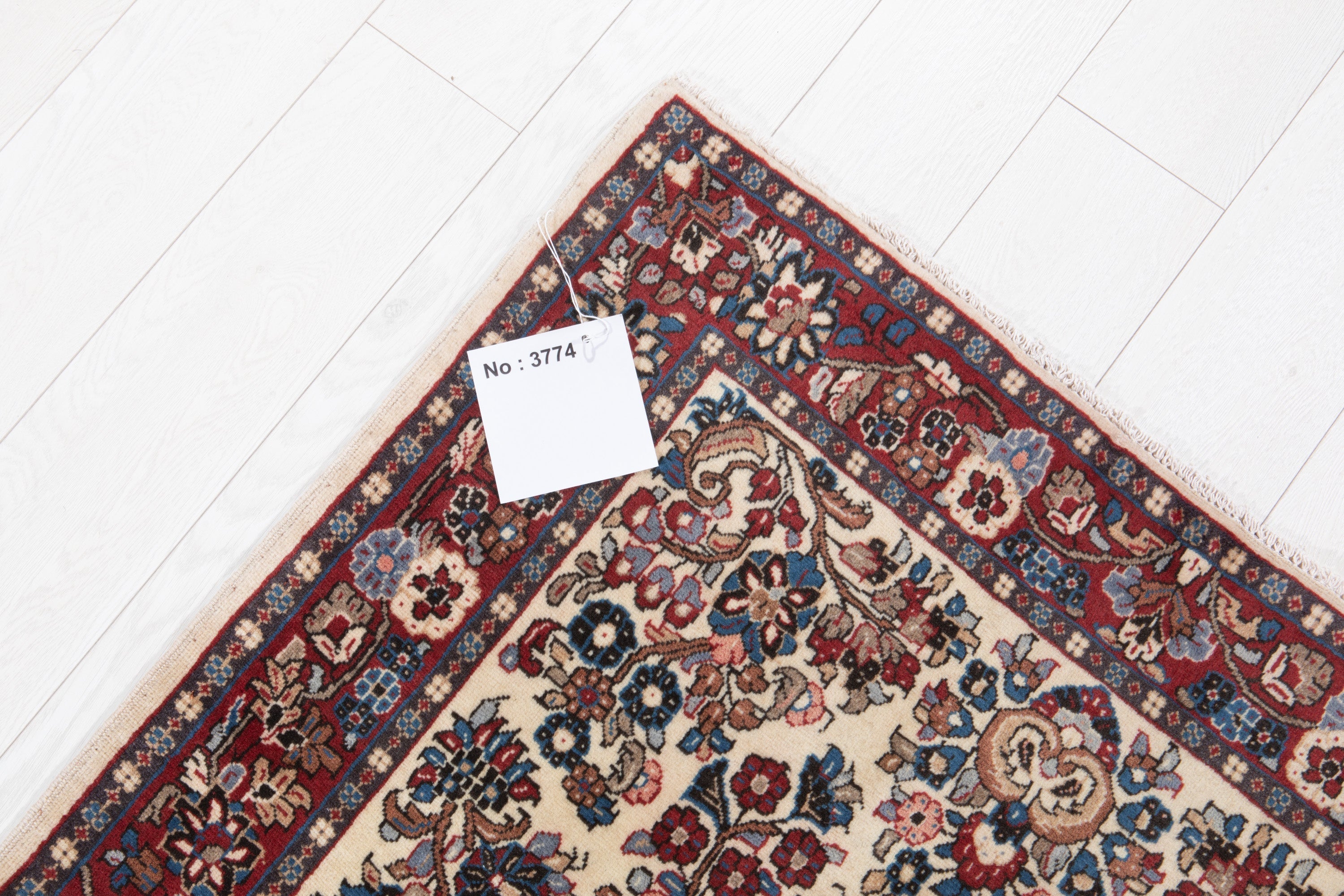 Corner of the rug with an attached inventory tag showing its rug number.