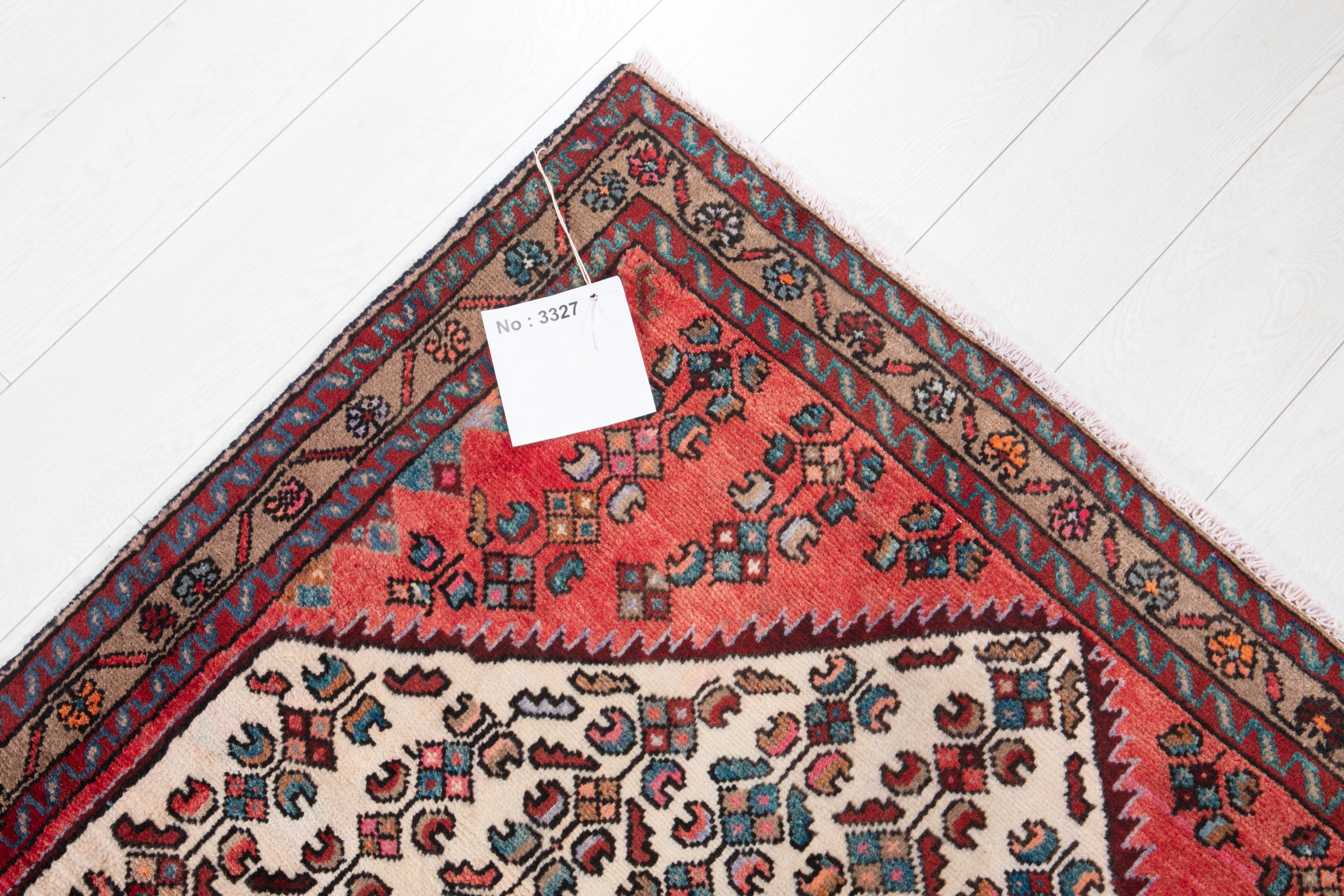 Folded corner detail of Hamadan Persian runner showing back weave, fringe, and border
