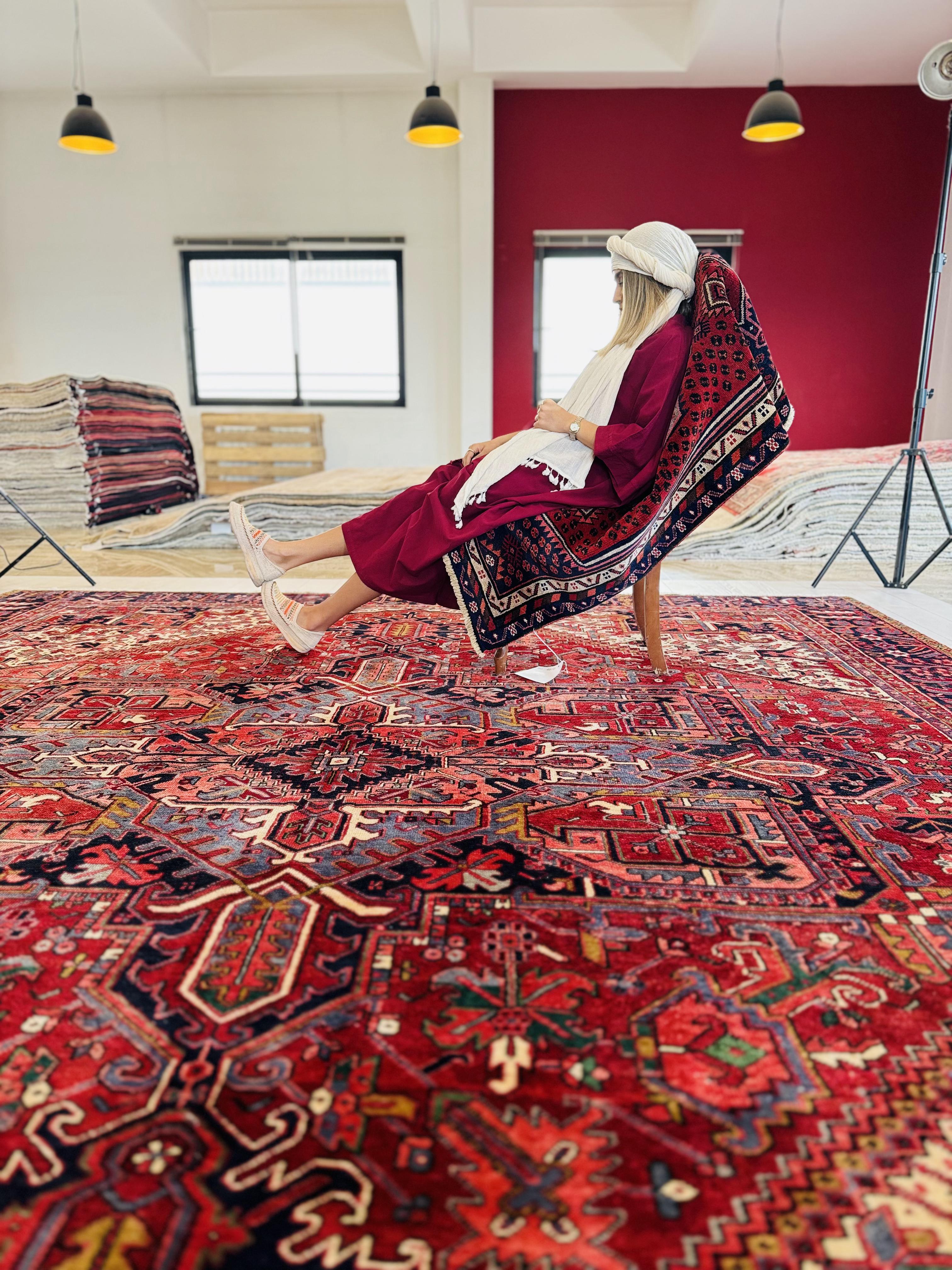 Lifestyle shot of a woman seated on a chair placed atop the rug in a showroom.