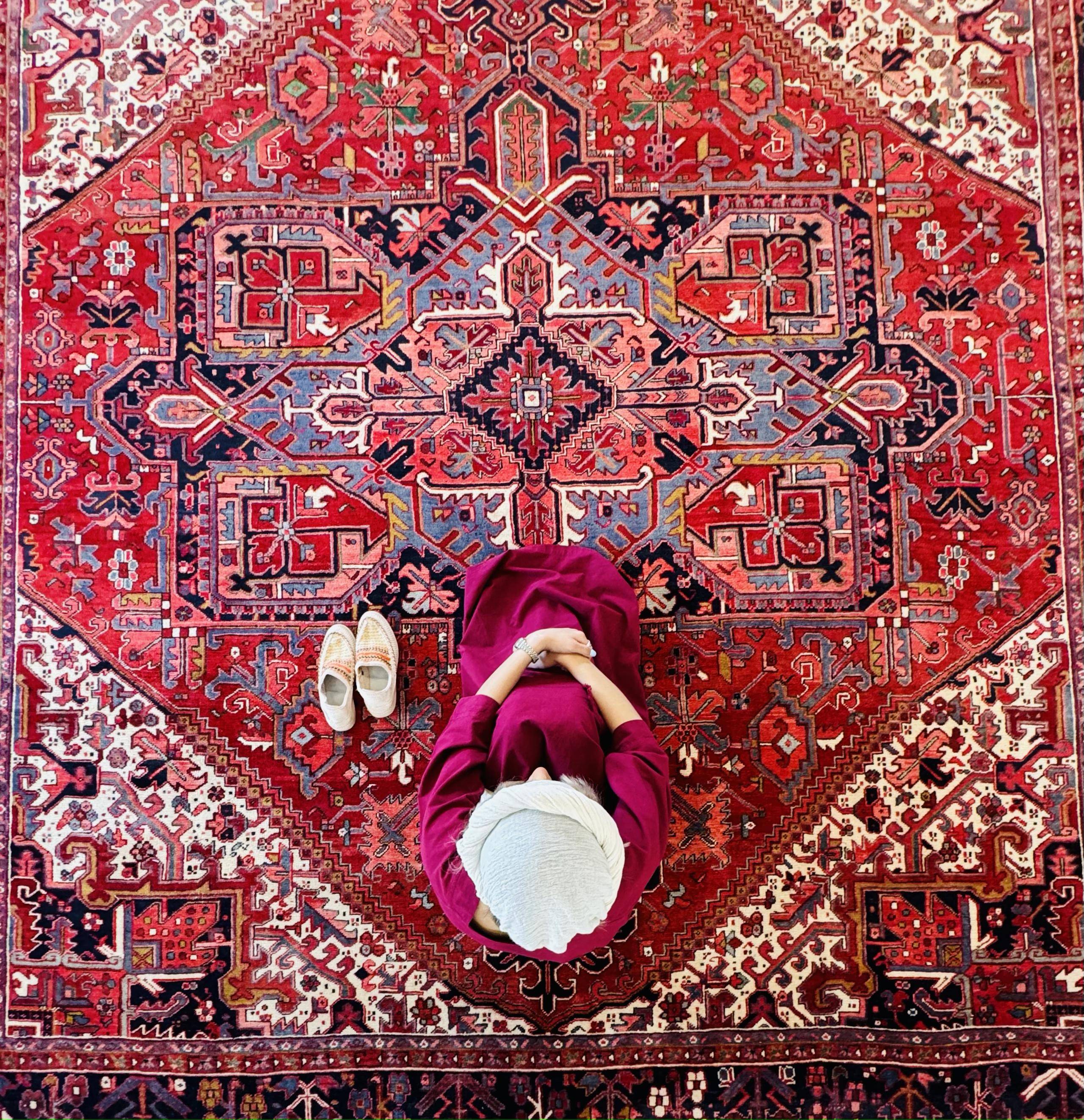 Overhead lifestyle shot of a person sitting on the rug's medallion with shoes beside them.