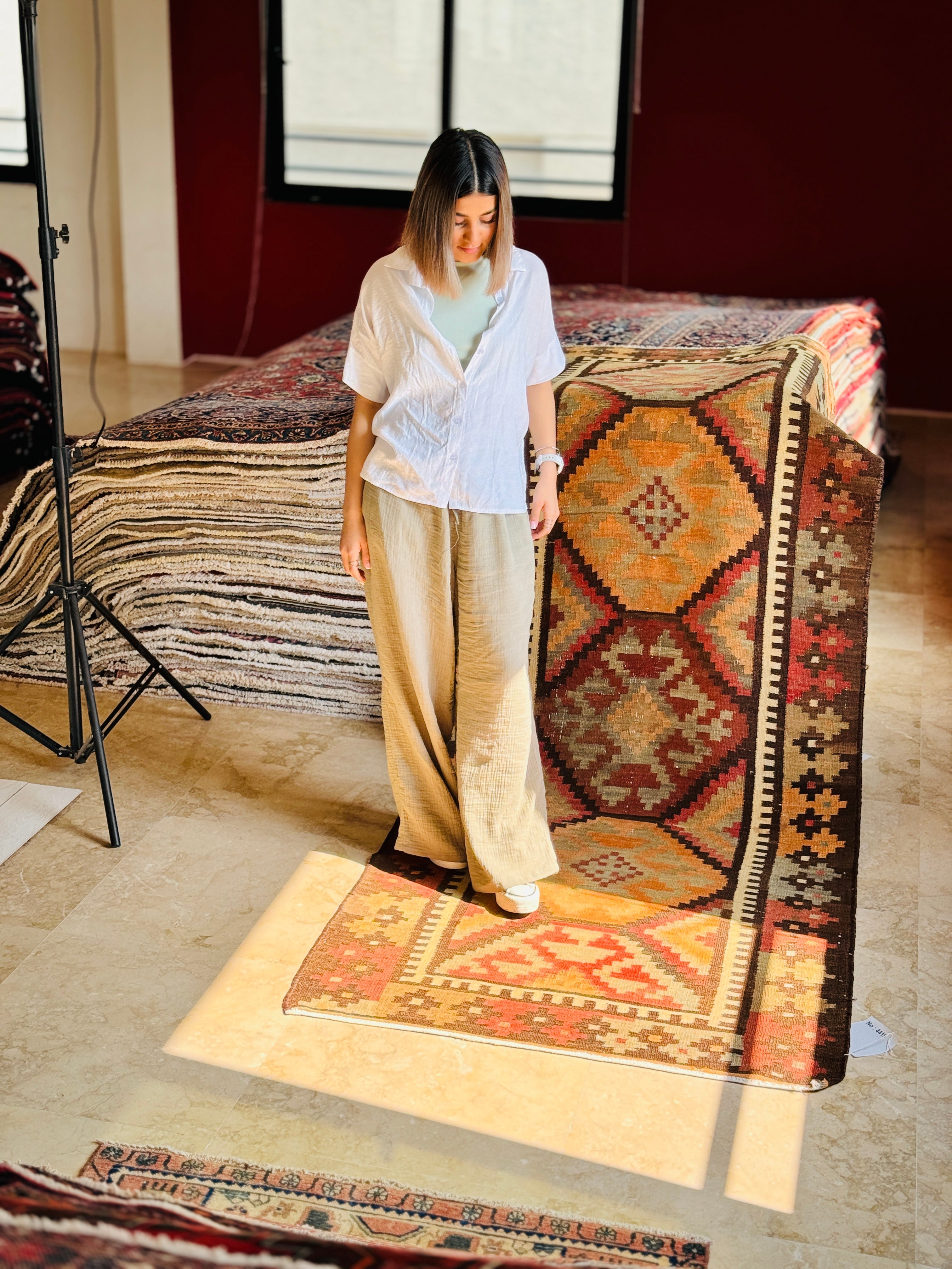 Studio photo shoot of the antique orange kilim runner hanging beside a woman posing.