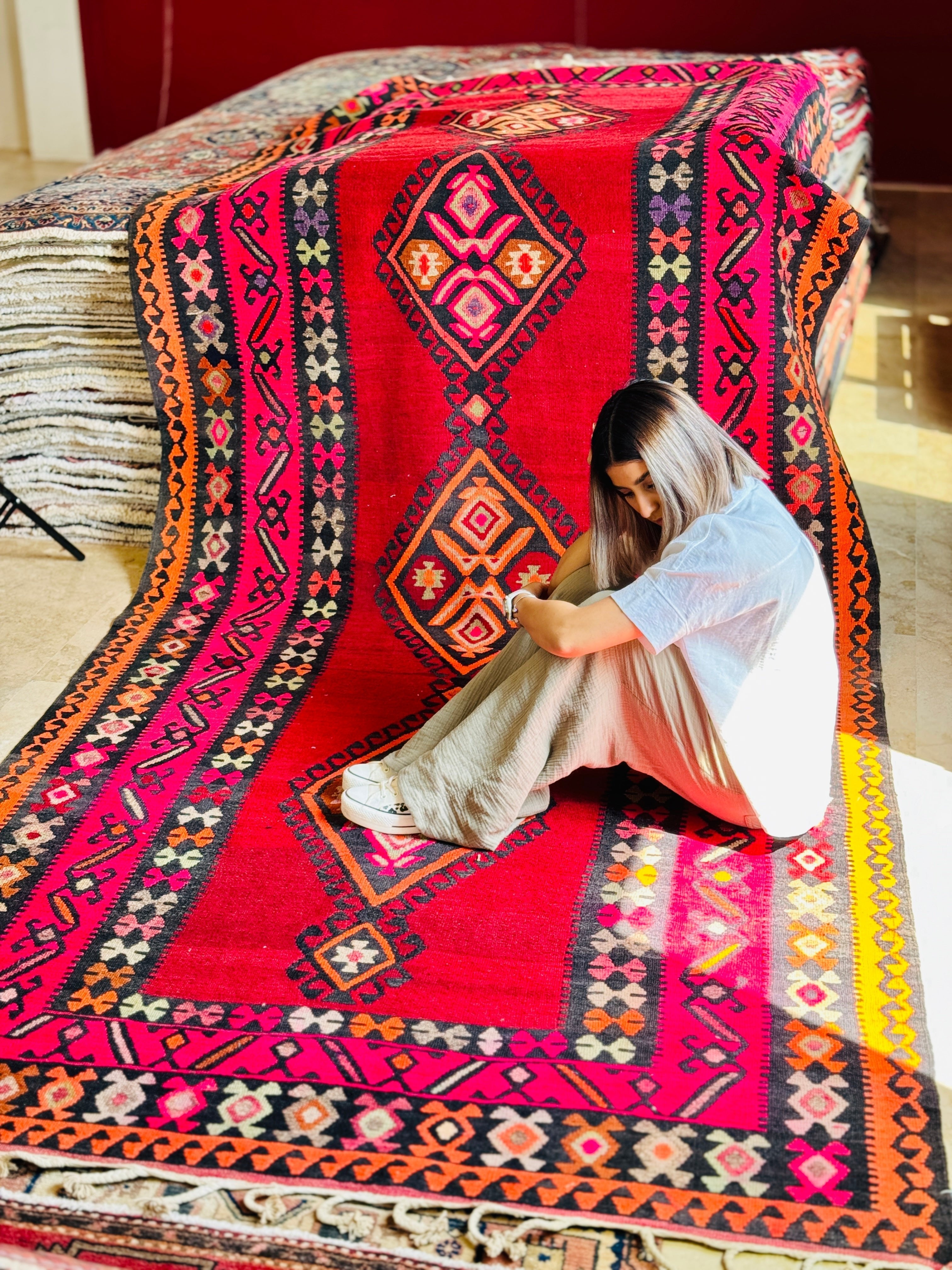 Lifestyle shot of a woman sitting on the red Persian kilim runner.