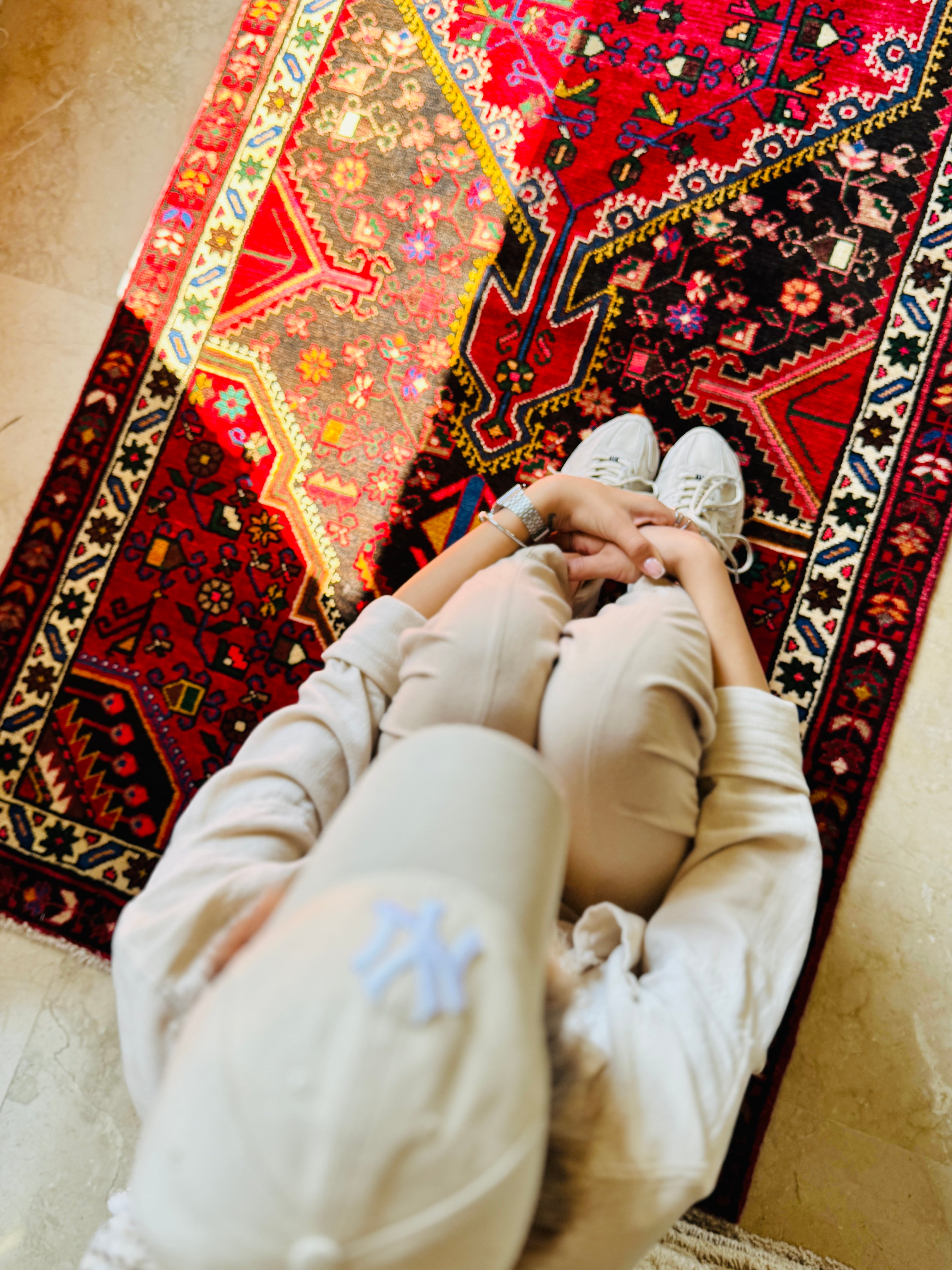 Person sitting on Hand-Knotted Vintage Wool Runner Rug – 9' 3" x 3' 5", showcasing its bold red and black tribal motifs in a cozy setting.