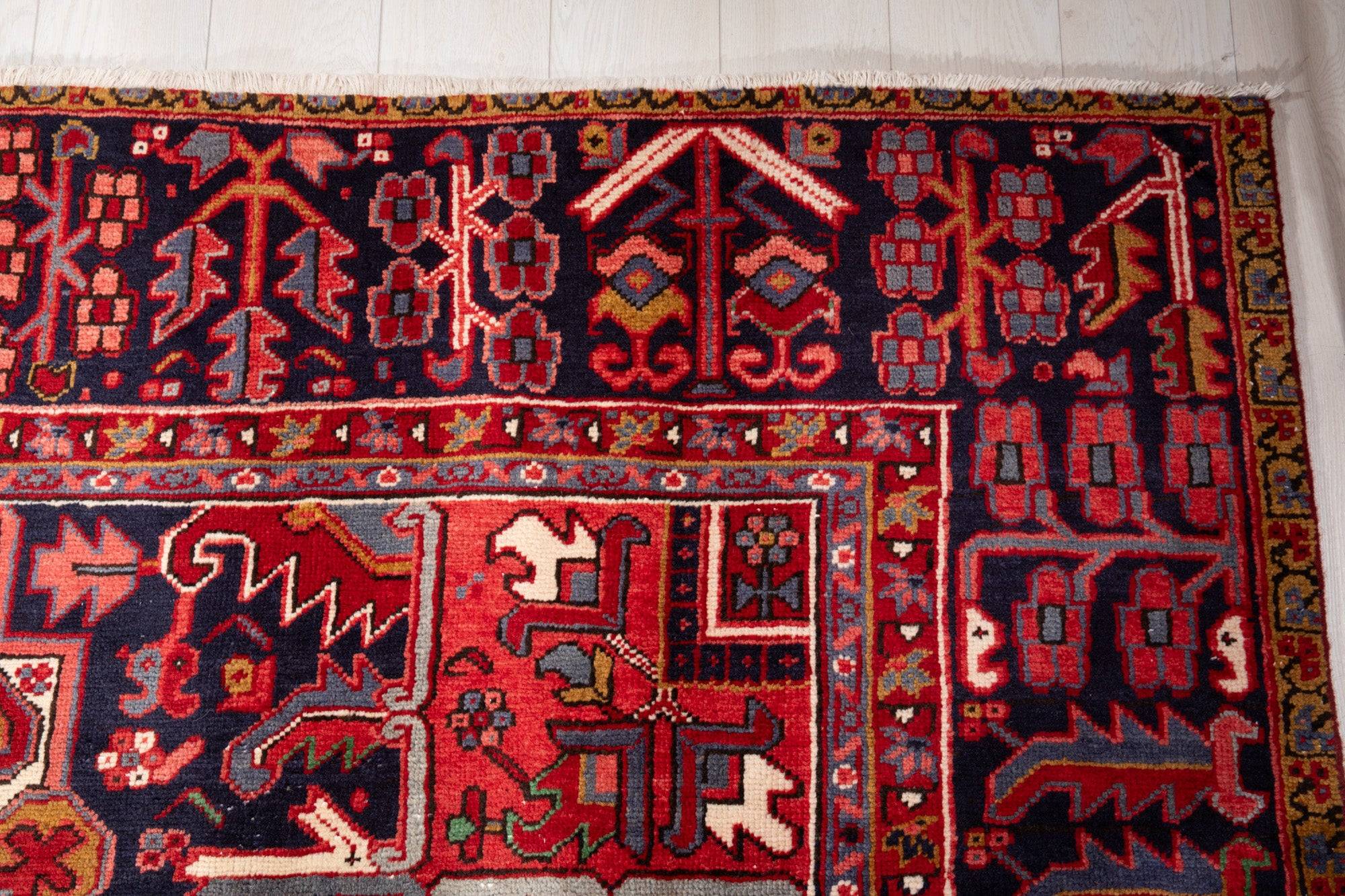 Corner close-up showing the navy field with tree and animal motifs beside the fringe.