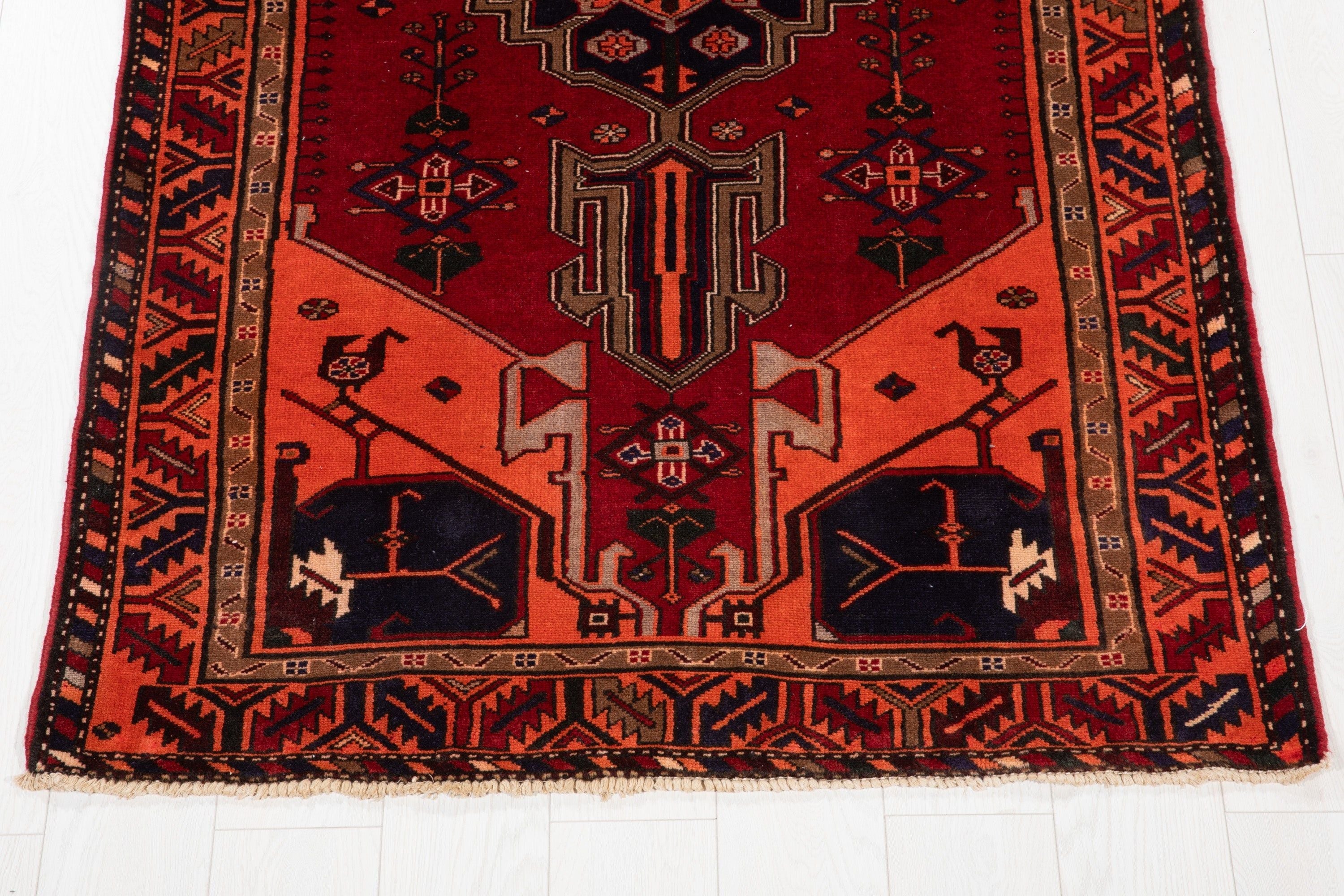 One end of the rug showing the fringe and bird motifs within the navy end panels.