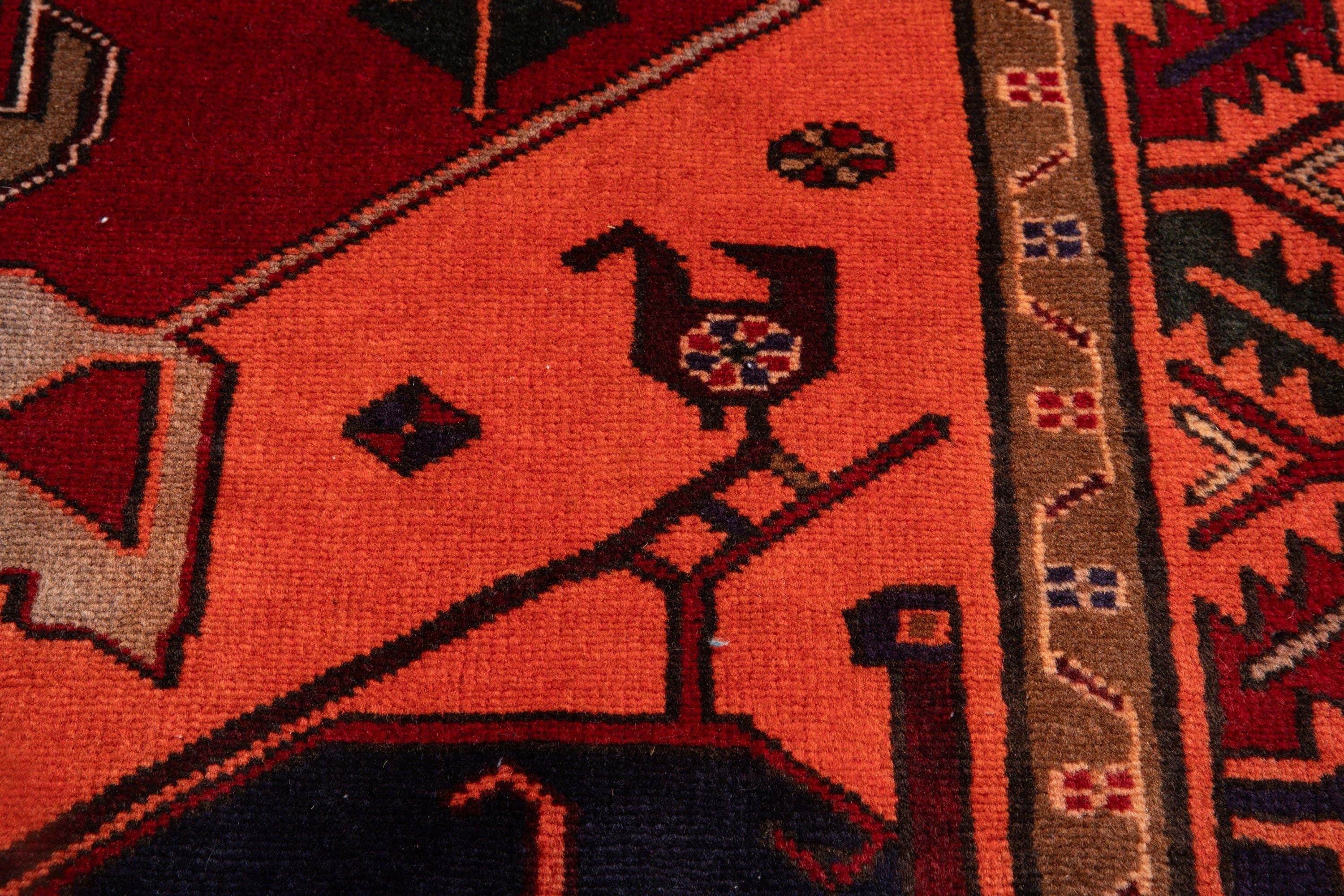 Close-up of a bird figure motif woven into the orange field of the rug.
